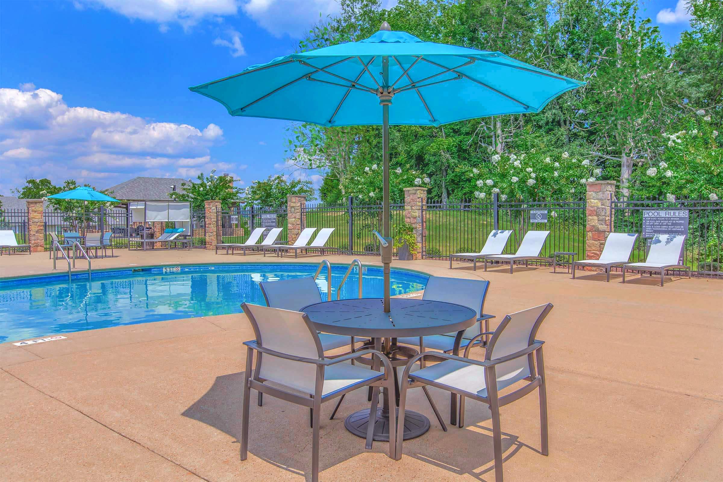 a chair sitting in front of a pool table with a blue umbrella