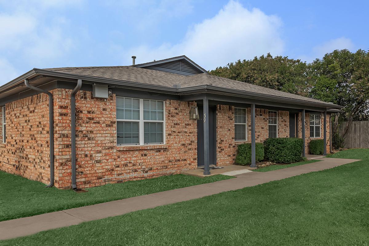 a large brick building with grass in front of a house