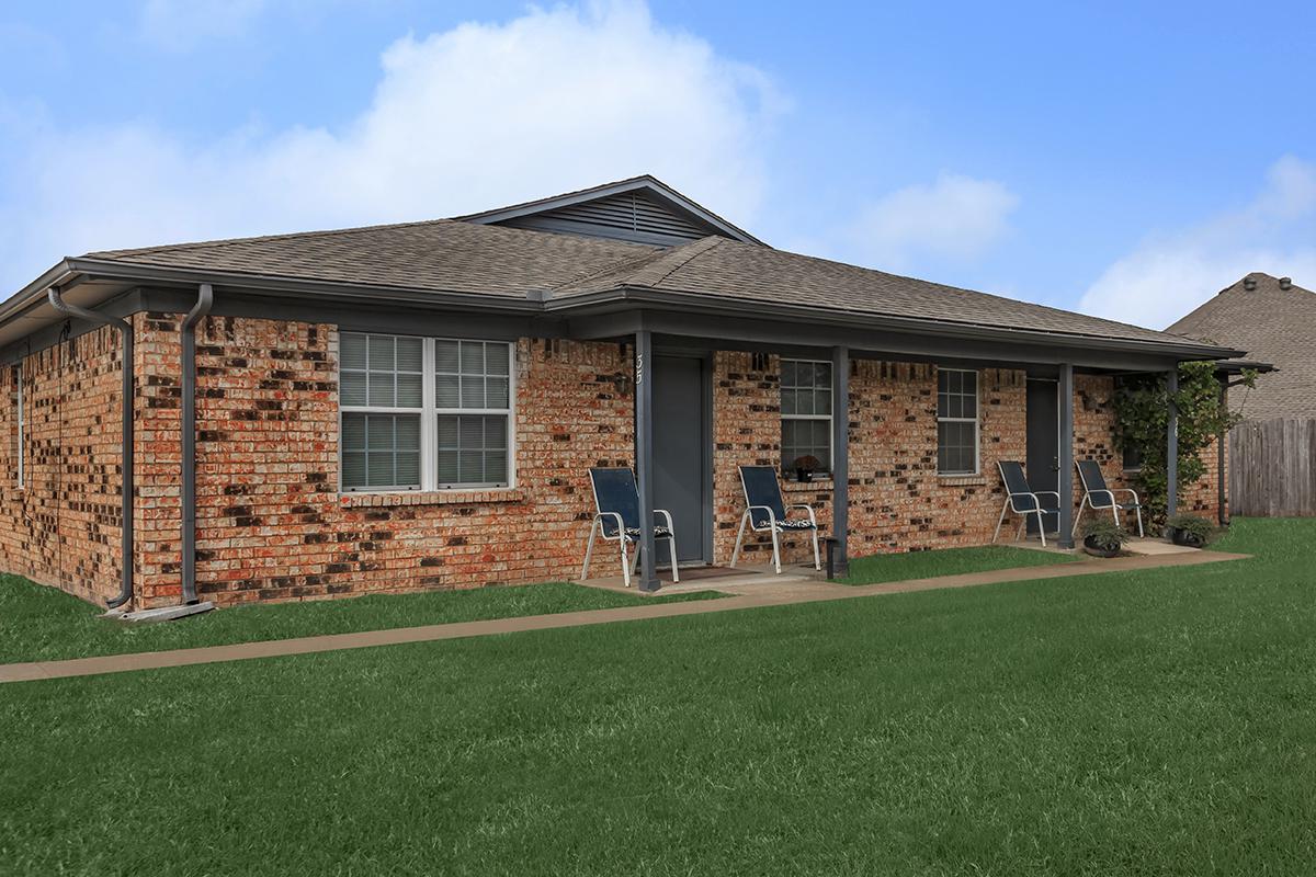 a large brick building with grass in front of a house