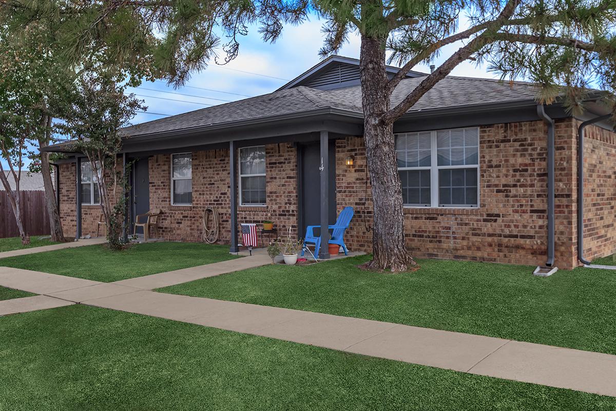 a house with a lawn in front of a brick building