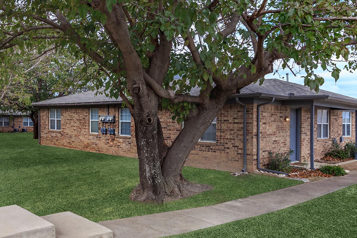 a house with a lawn in front of a brick building