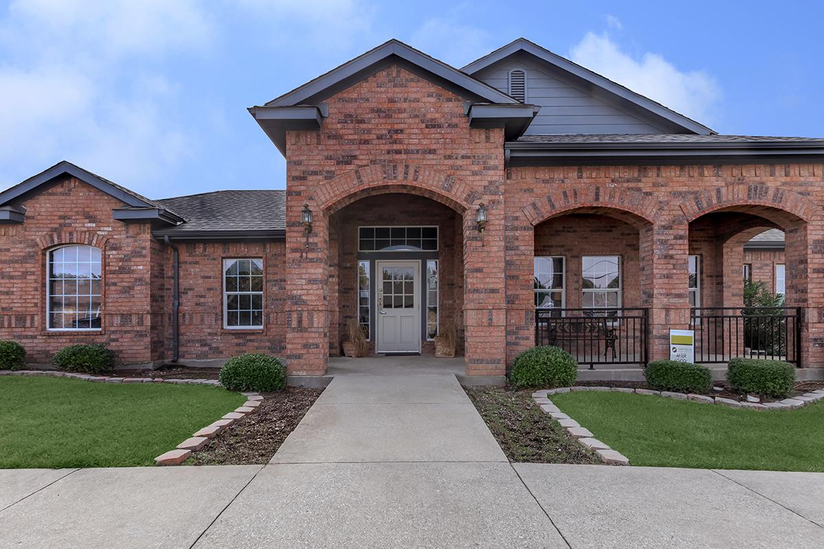 a large brick building with grass in front of a house