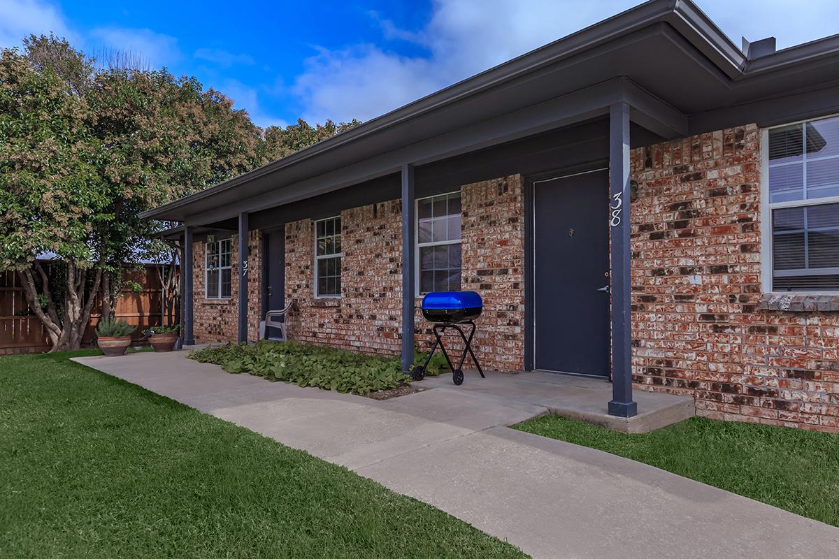 a house with a lawn in front of a brick building