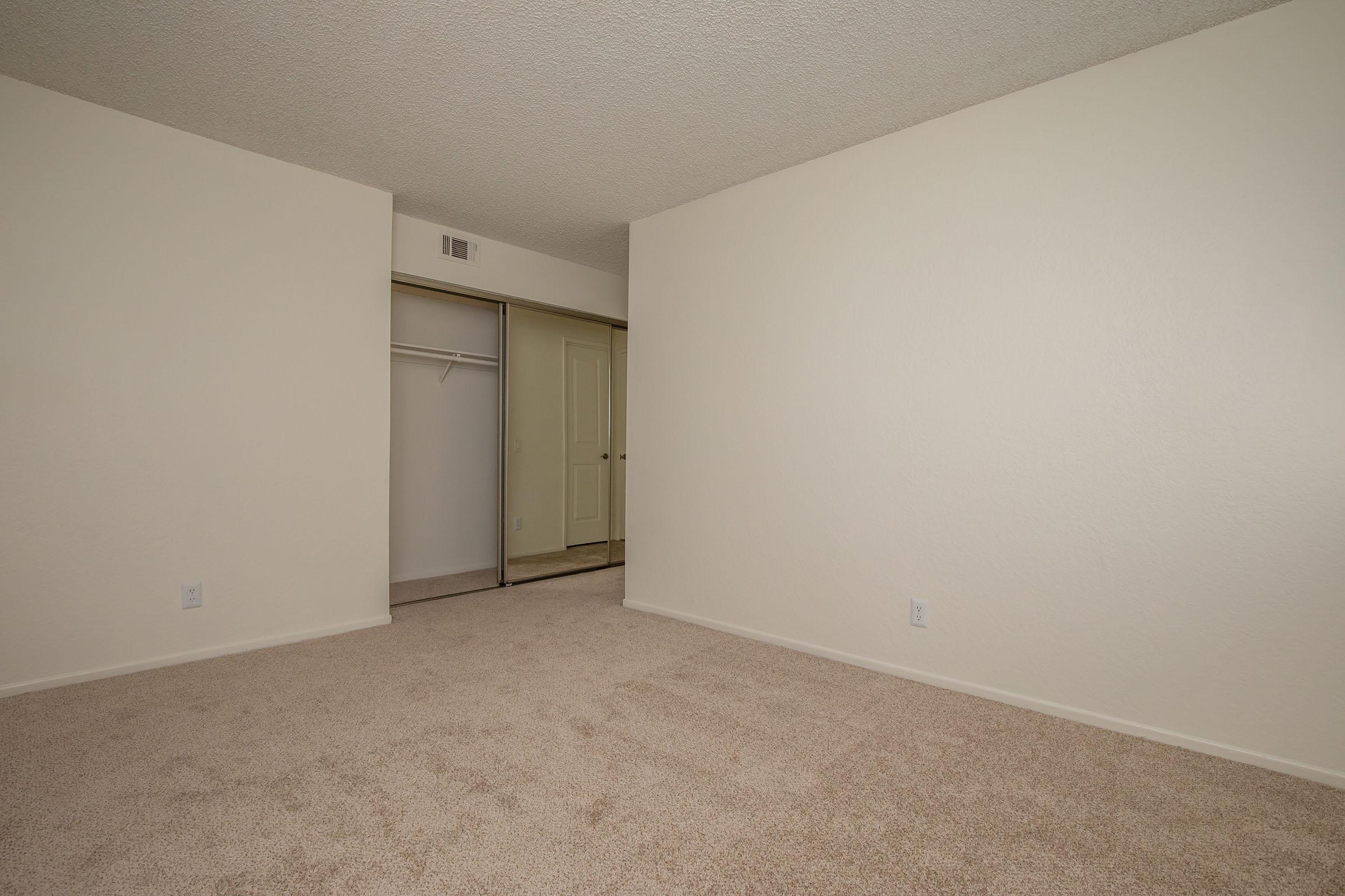 carpeted bedroom with sliding mirror glass closet doors