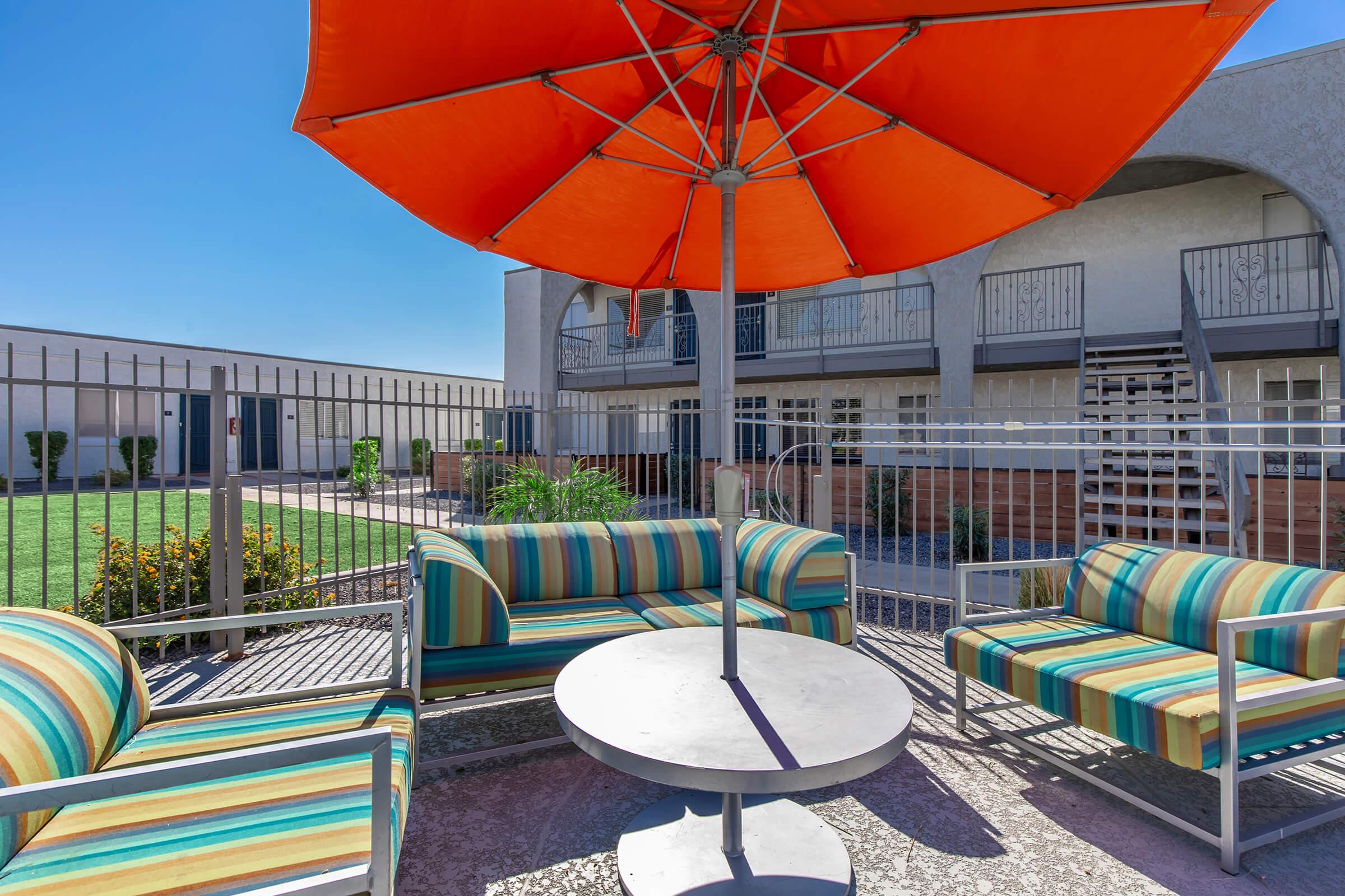 a group of lawn chairs sitting on top of a colorful umbrella