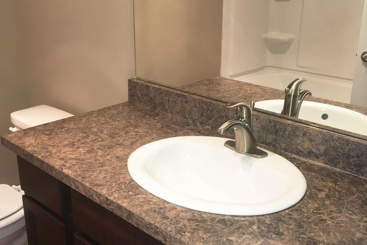 a white sink sitting under a mirror