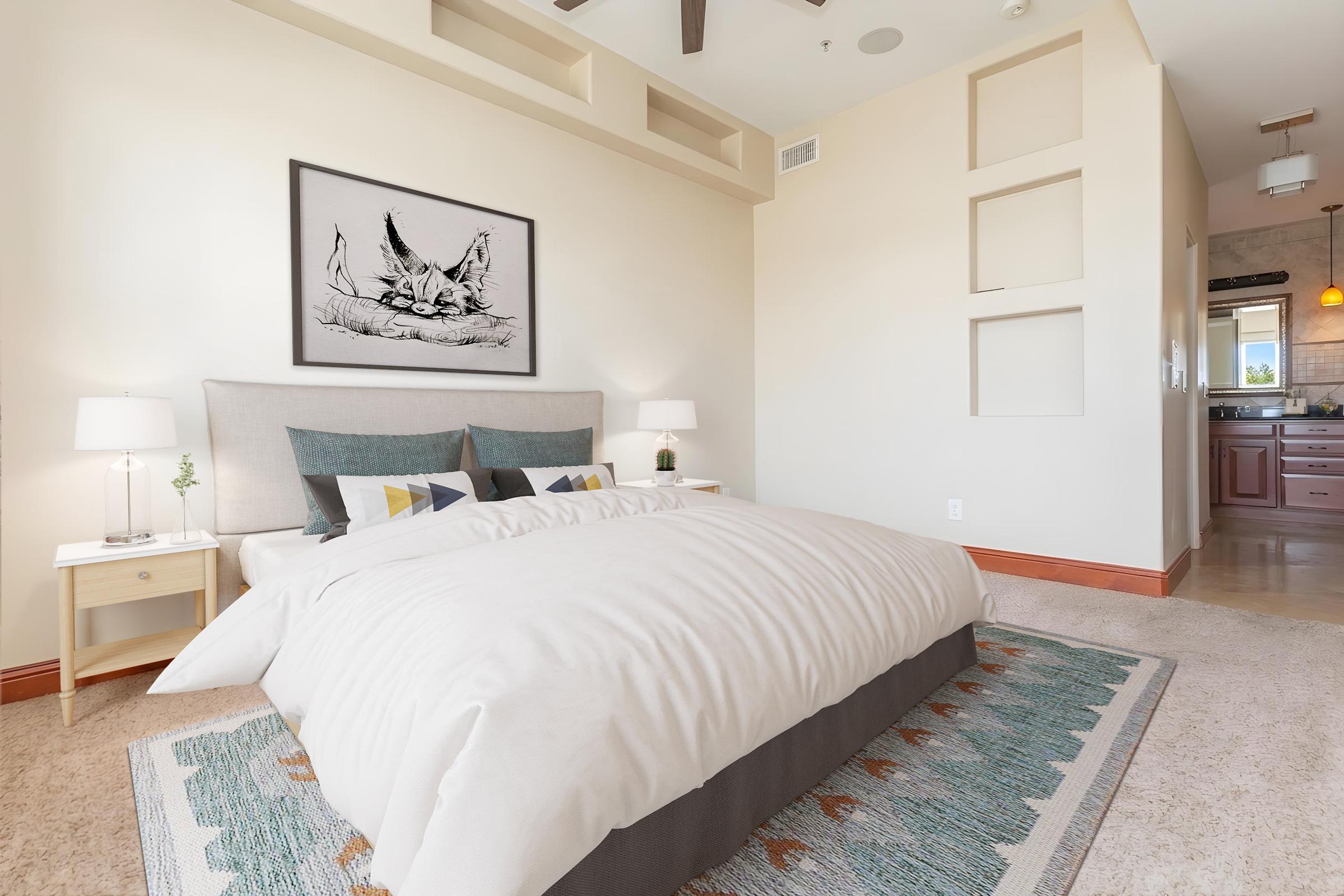 A bright and modern bedroom featuring a plush white bed with patterned pillows, a large artwork of a cat on the wall, two bedside lamps on wooden tables, and a cozy rug. The room has soft pastel walls, high ceilings, and a warm ambiance.