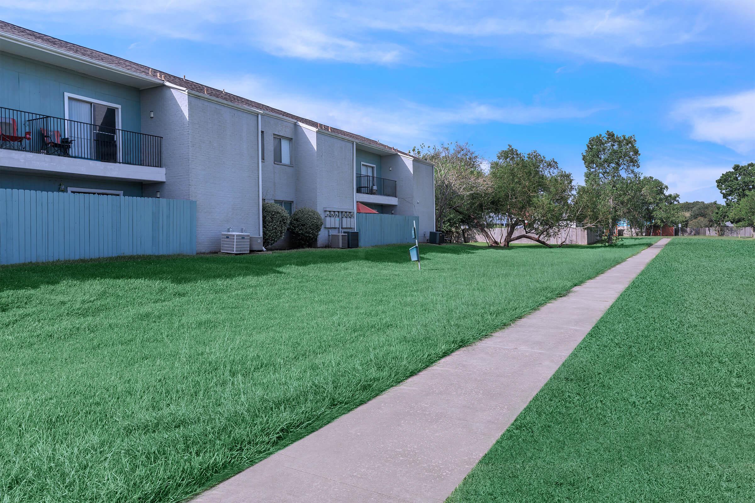 a large brick building with green grass