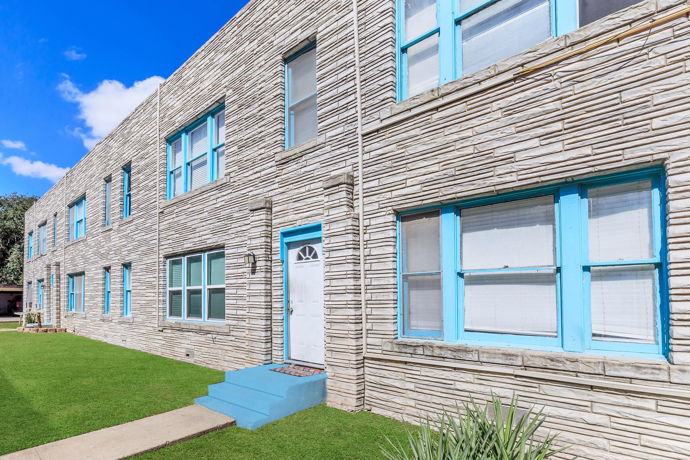 a large brick building with grass in front of a window