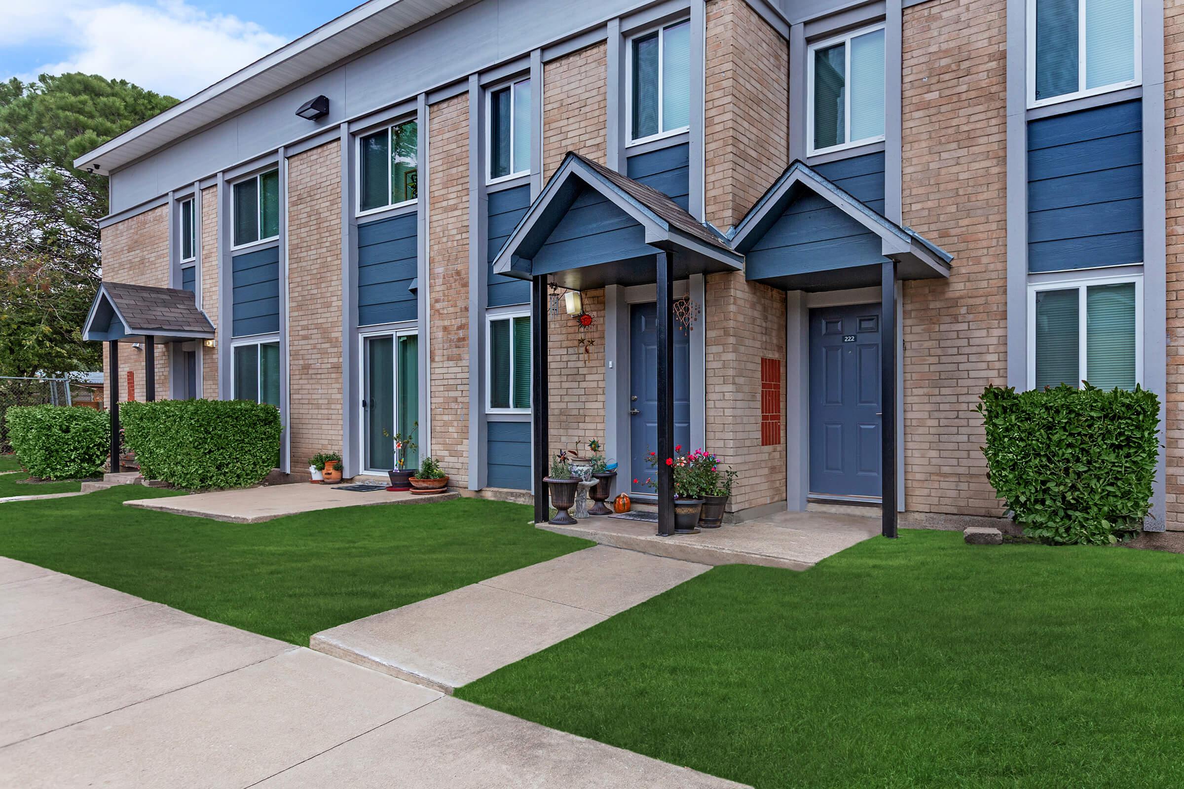 a large brick building with grass in front of a house