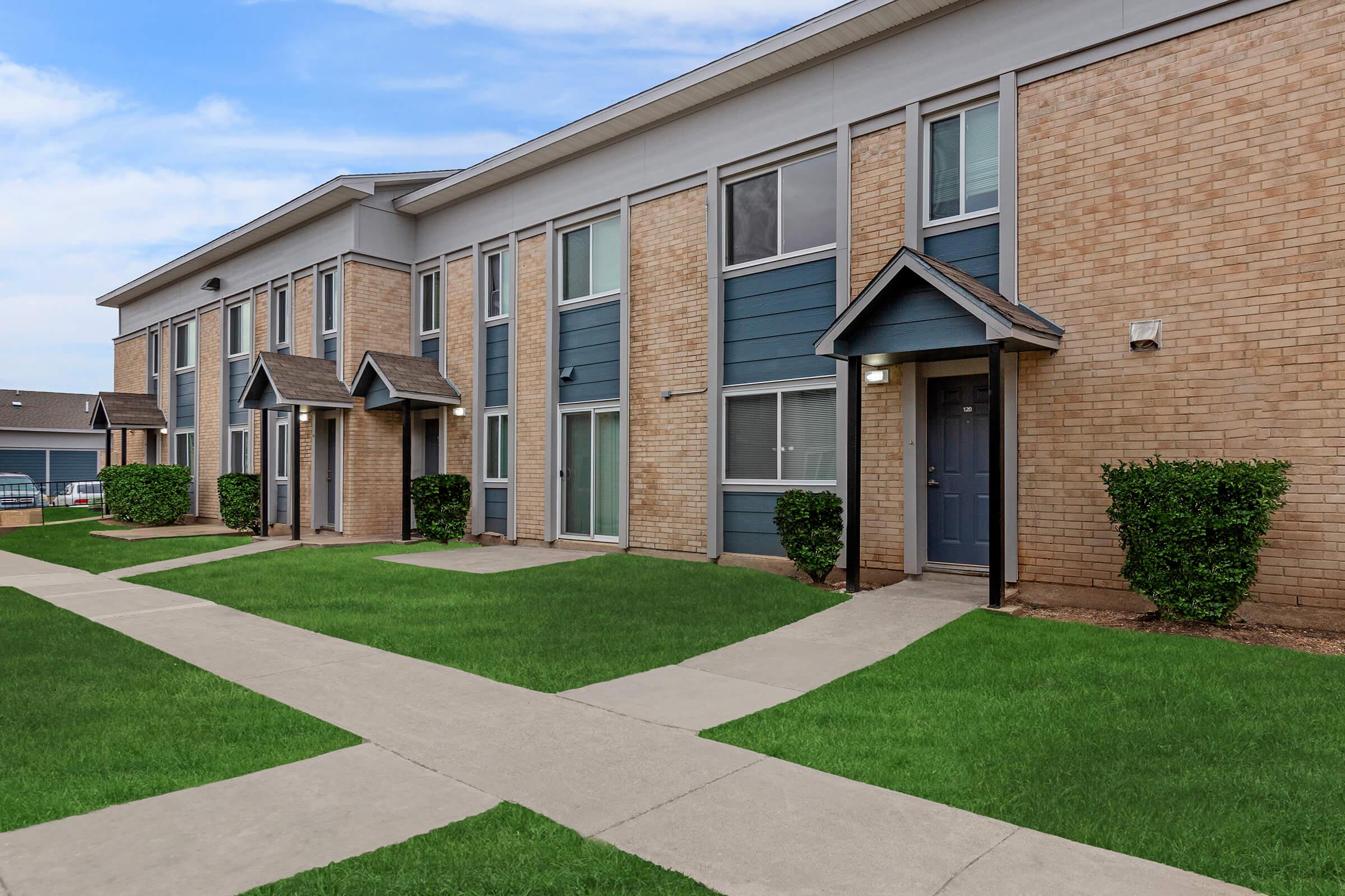 a large brick building with grass in front of a house