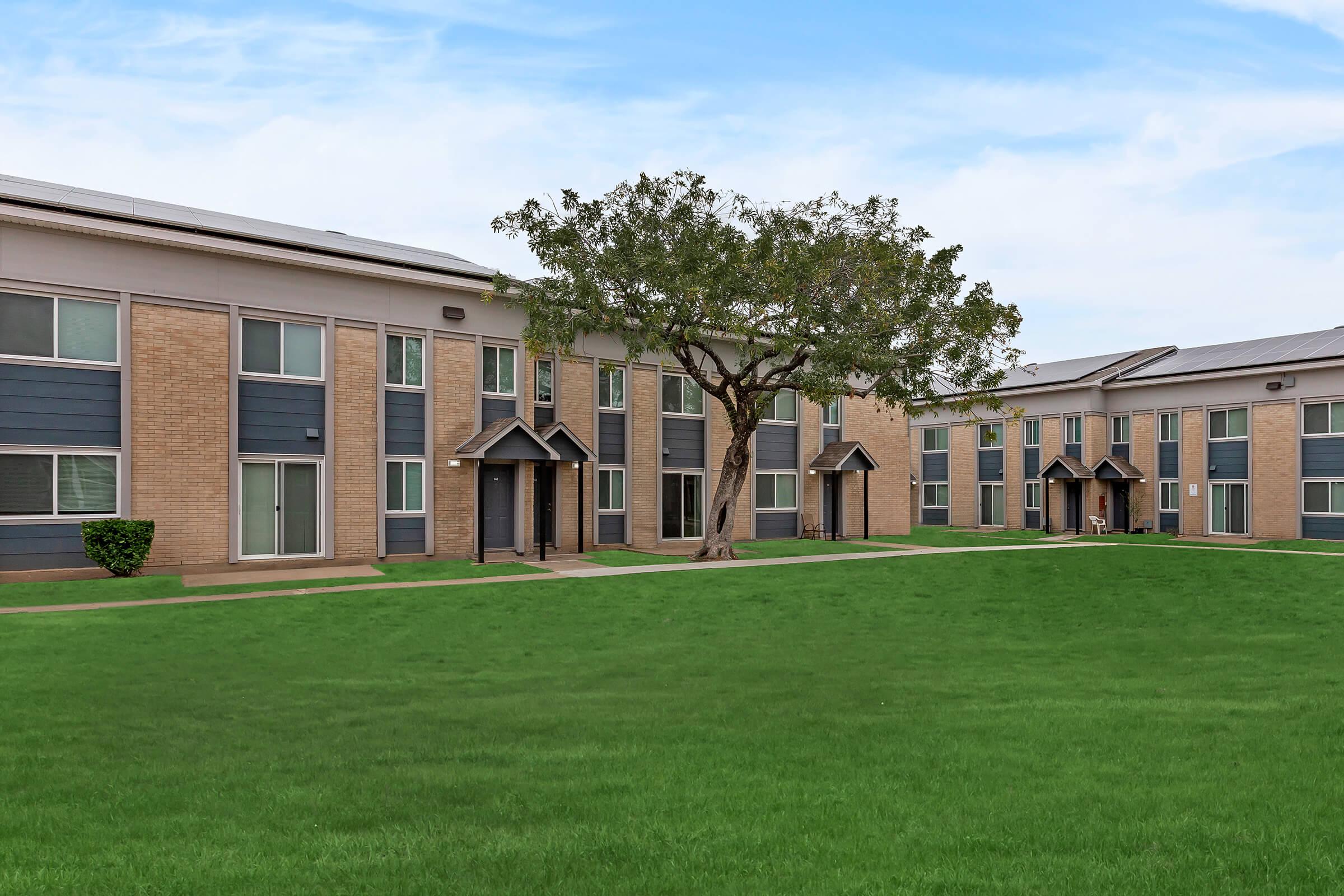 a large brick building with grass in front of a house