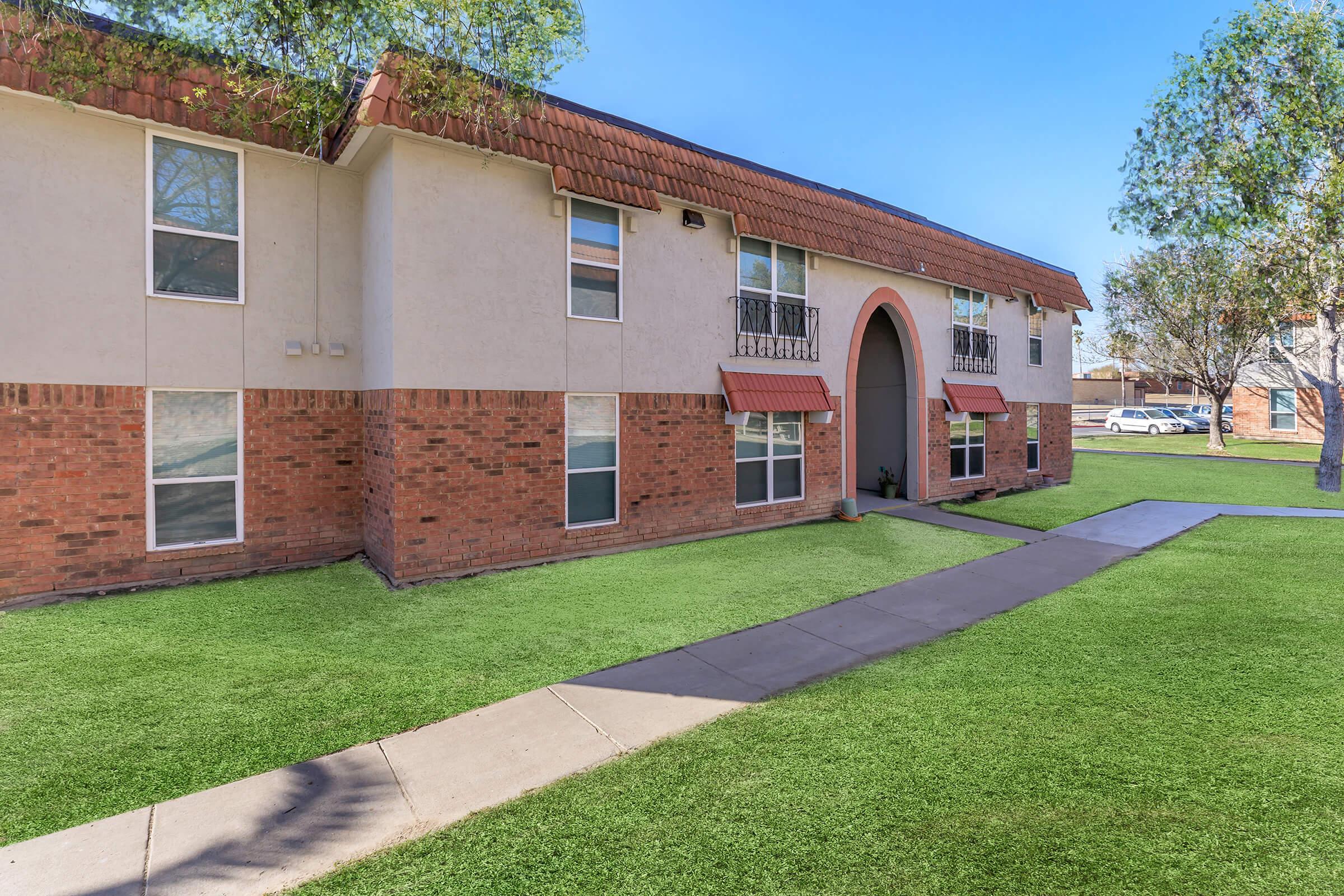 a large brick building with grass in front of a house