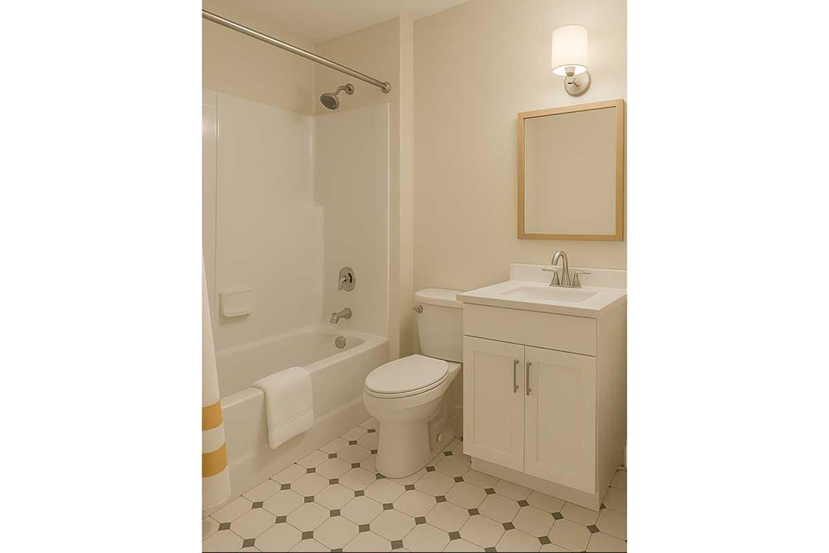 A clean and modern bathroom featuring a white tub with a shower, a toilet, and a vanity sink with a mirror. The floor is tiled with hexagonal patterns, and soft lighting is provided by a wall-mounted sconce. White towels are neatly arranged on the tub's edge.