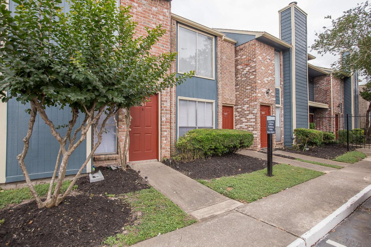 a house with bushes in front of a brick building