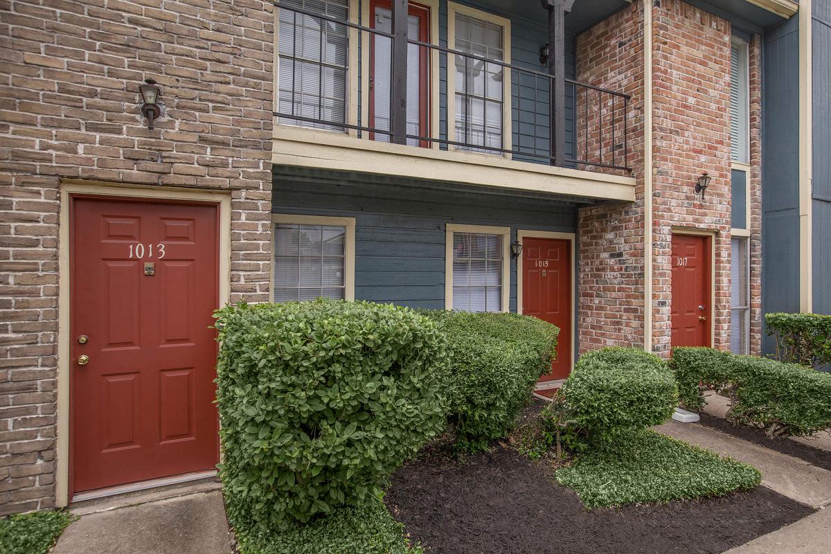 a house with bushes in front of a brick building