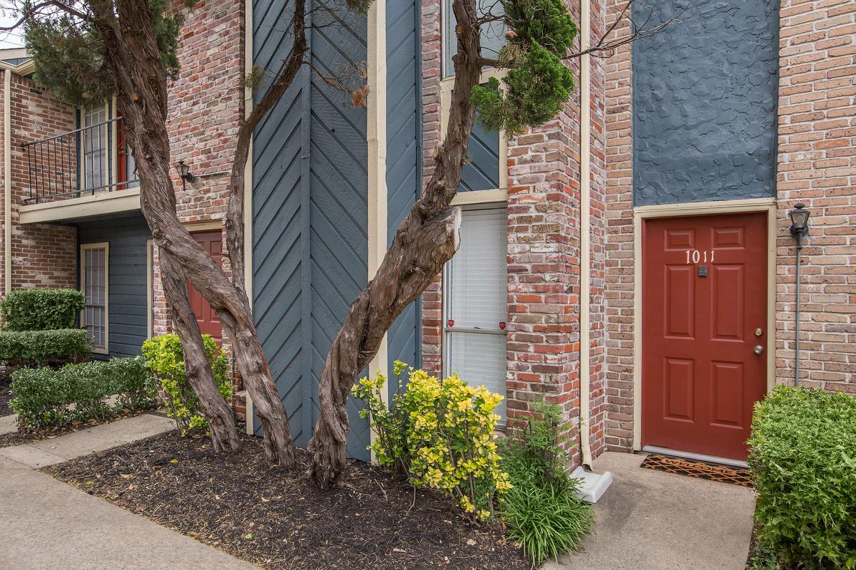 a house with bushes in front of a brick building