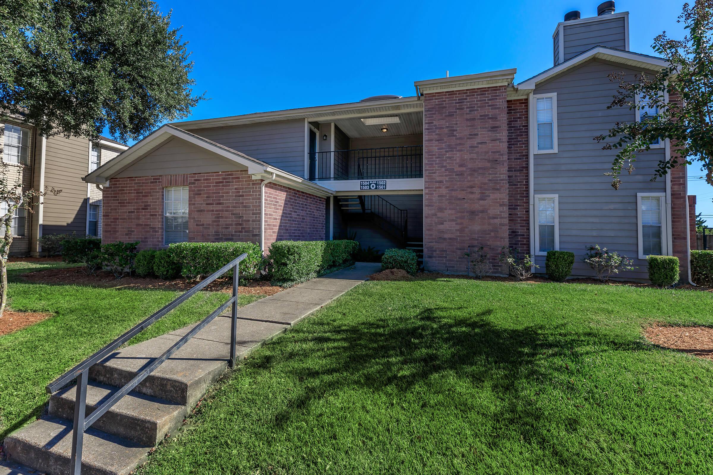 a house with a lawn in front of a brick building