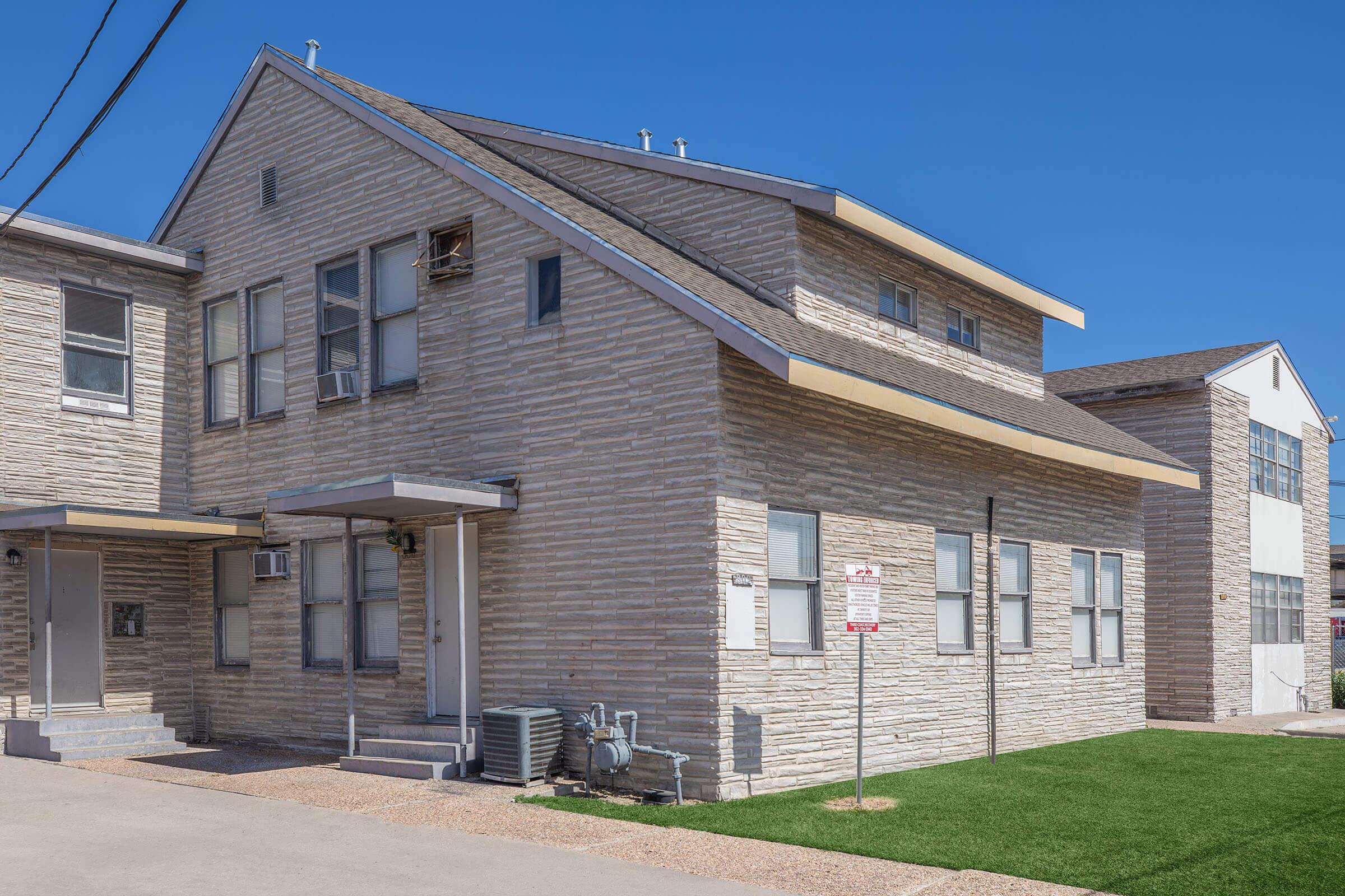 a large brick building with grass in front of a house