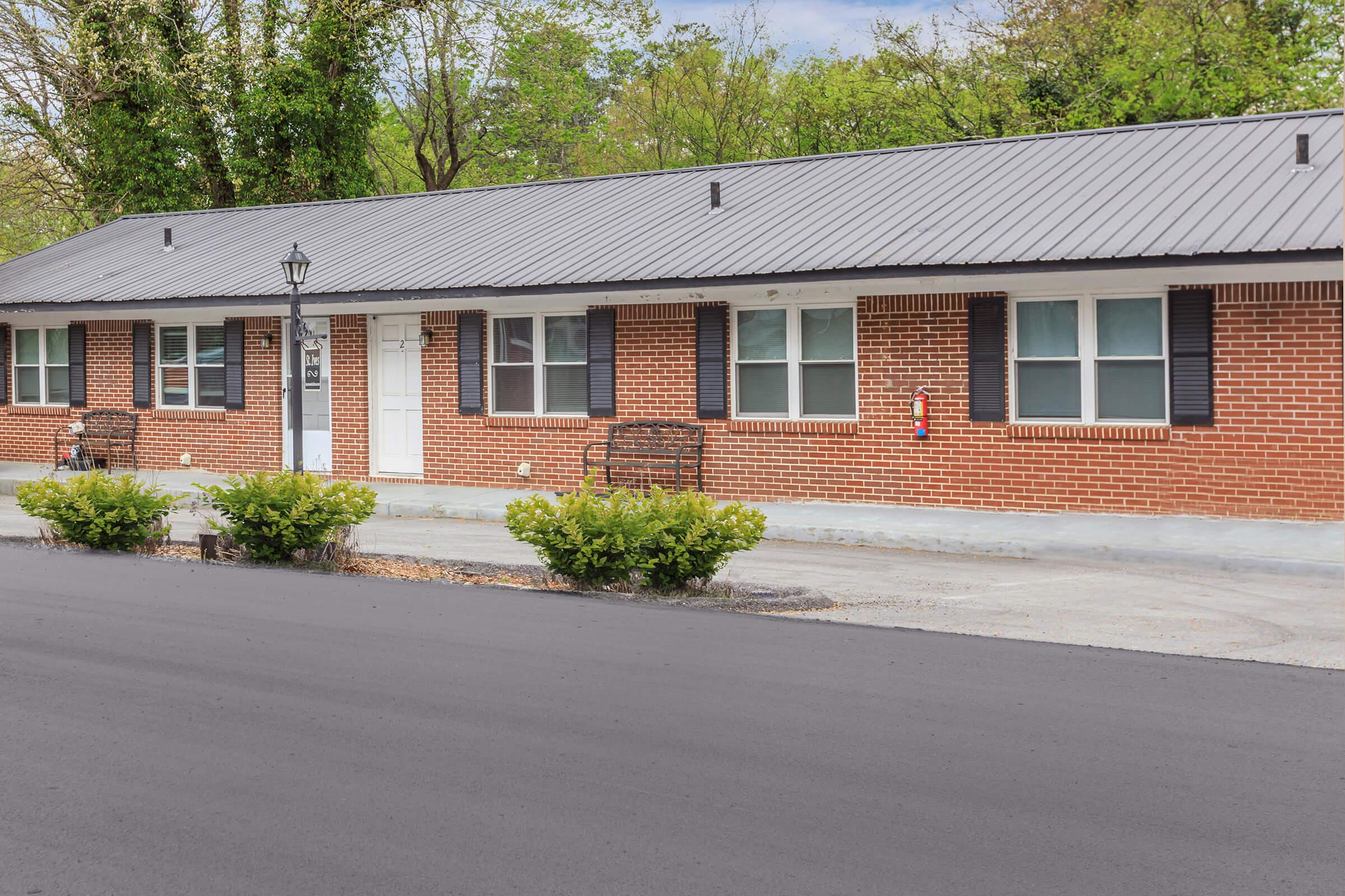 a house with bushes in front of a brick building