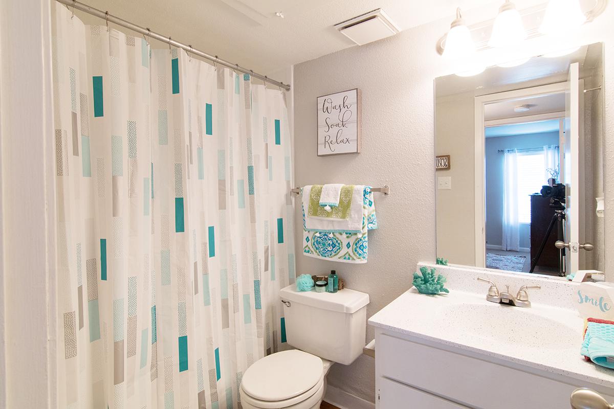 a white sink sitting under a mirror