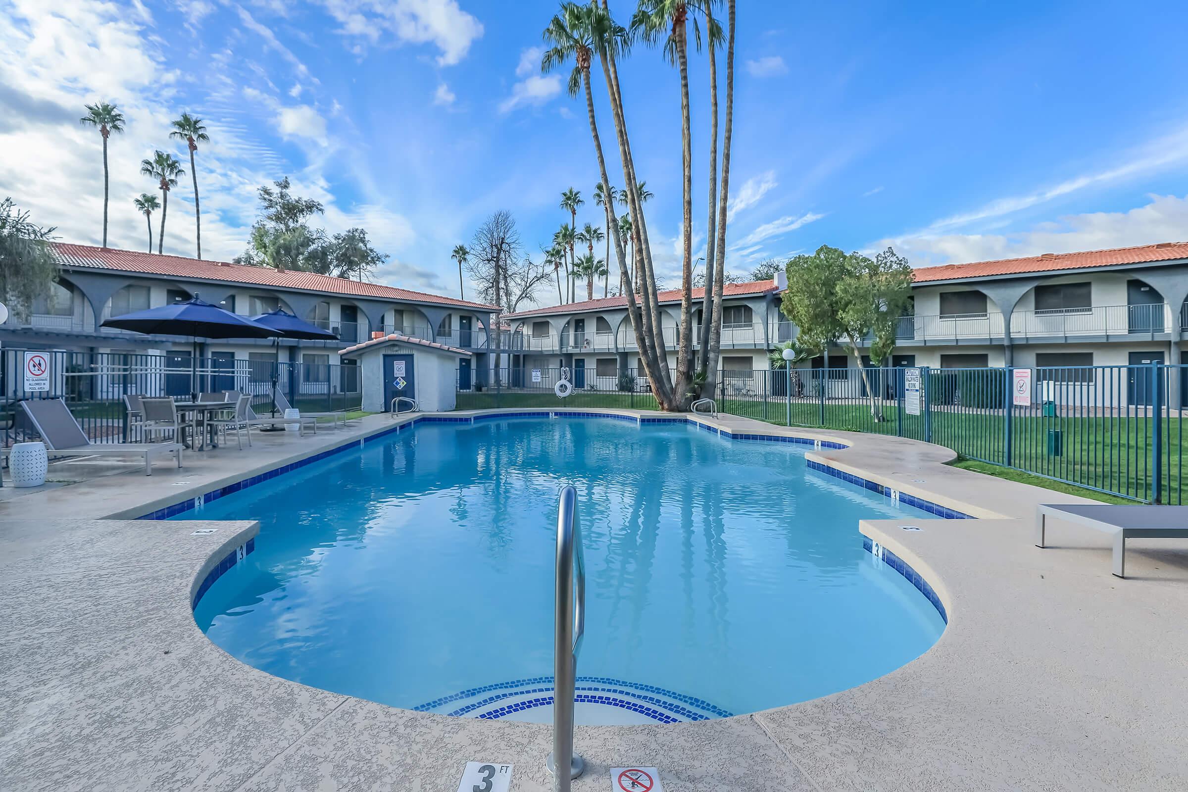 Large outdoor pool with view of a 2 story apartment building behind it