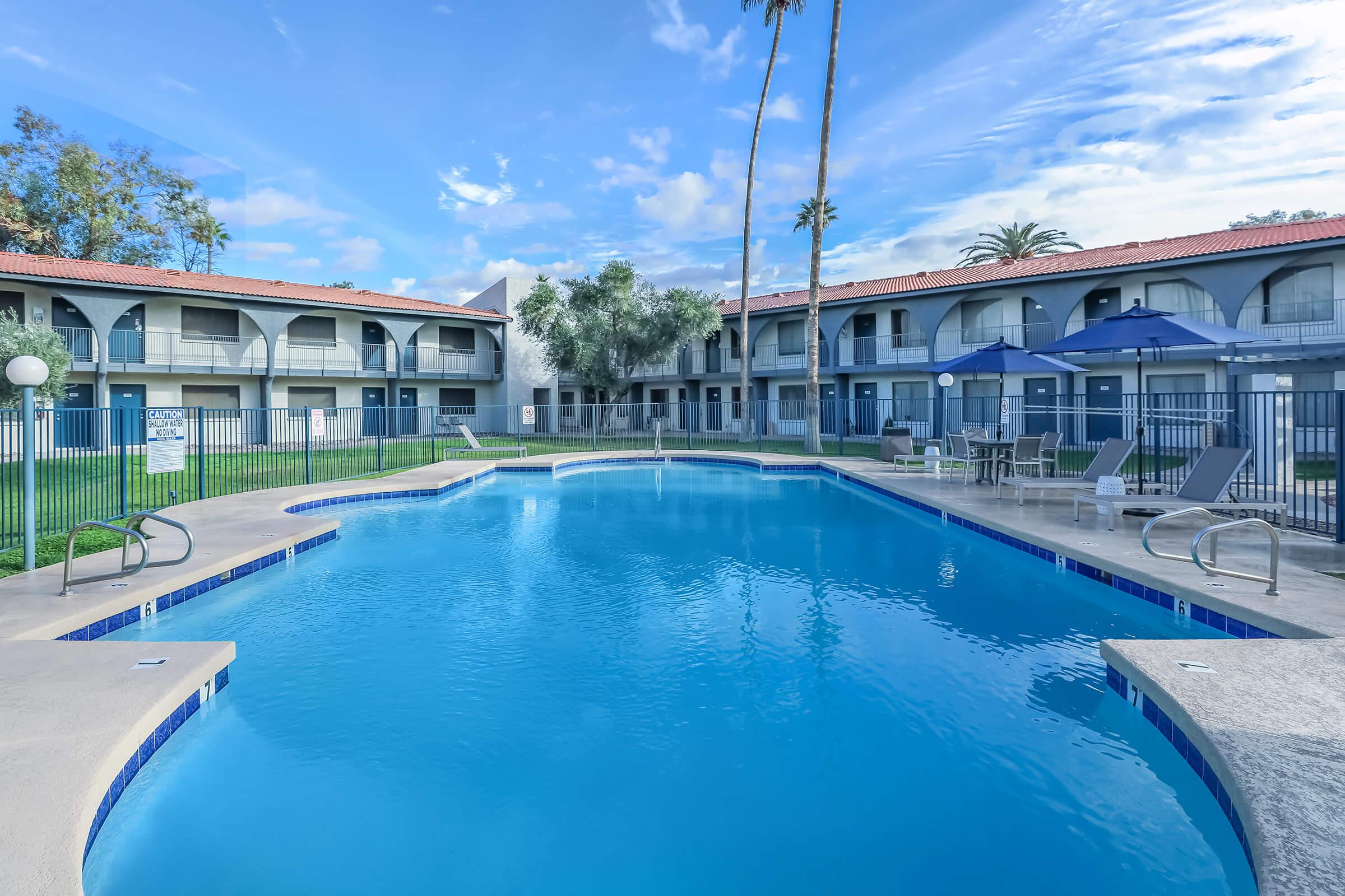 Large outdoor pool with view of a 2 story apartment building behind it