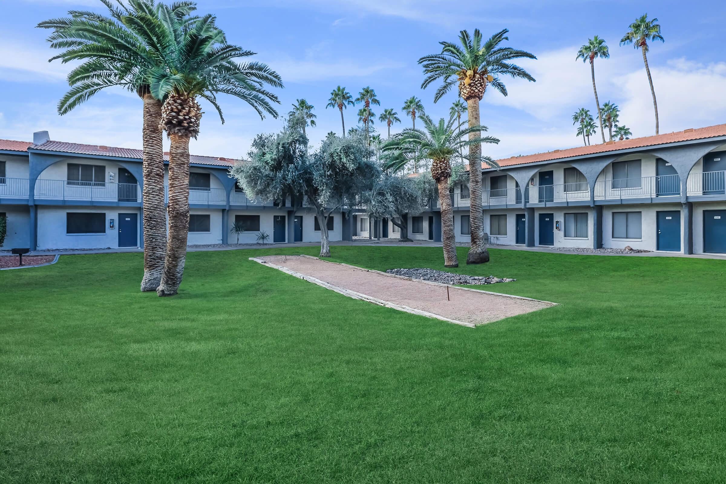 Apartment building grass court yard with horse shoe game and palm trees