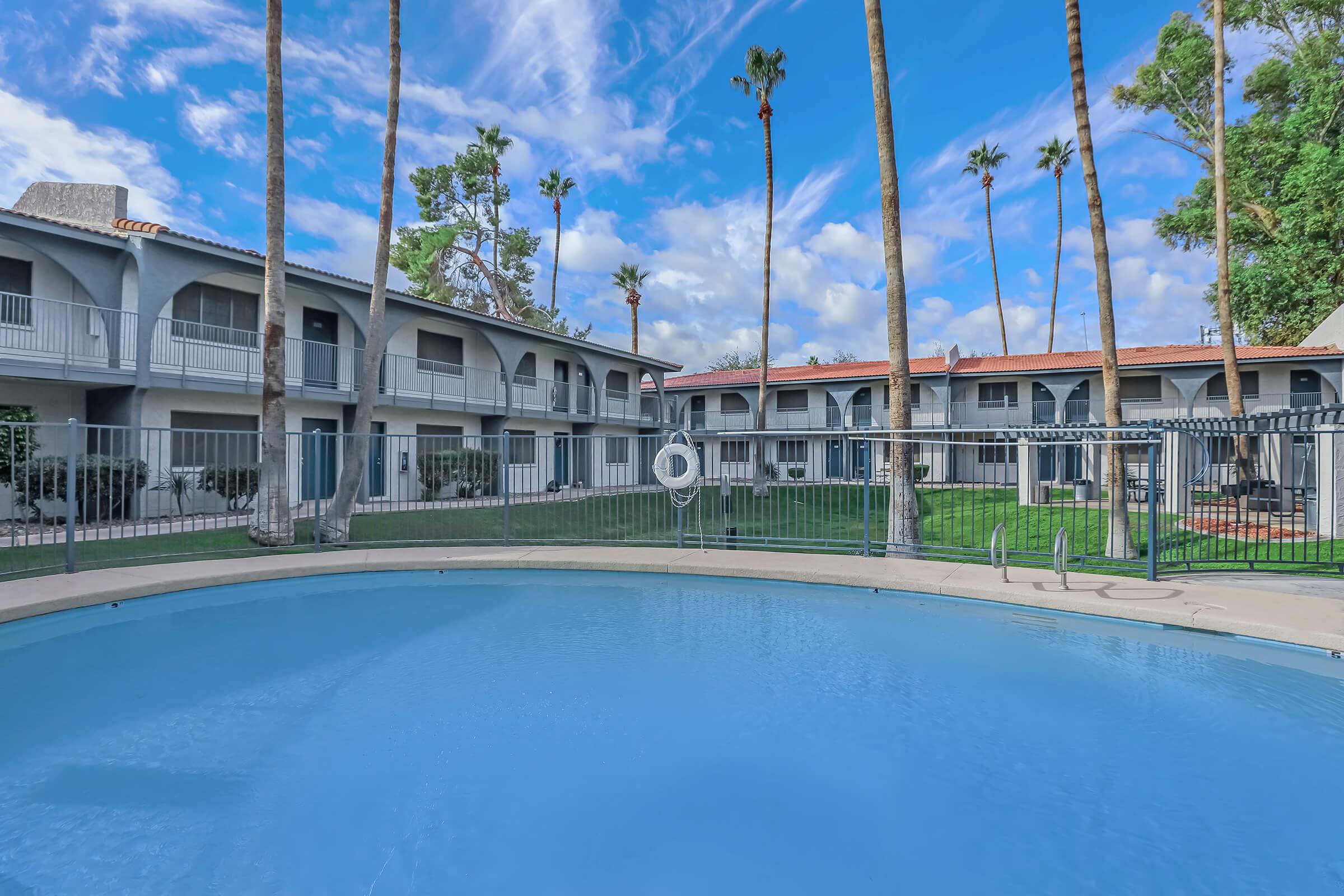 Large outdoor pool with view of a 2 story apartment building behind it