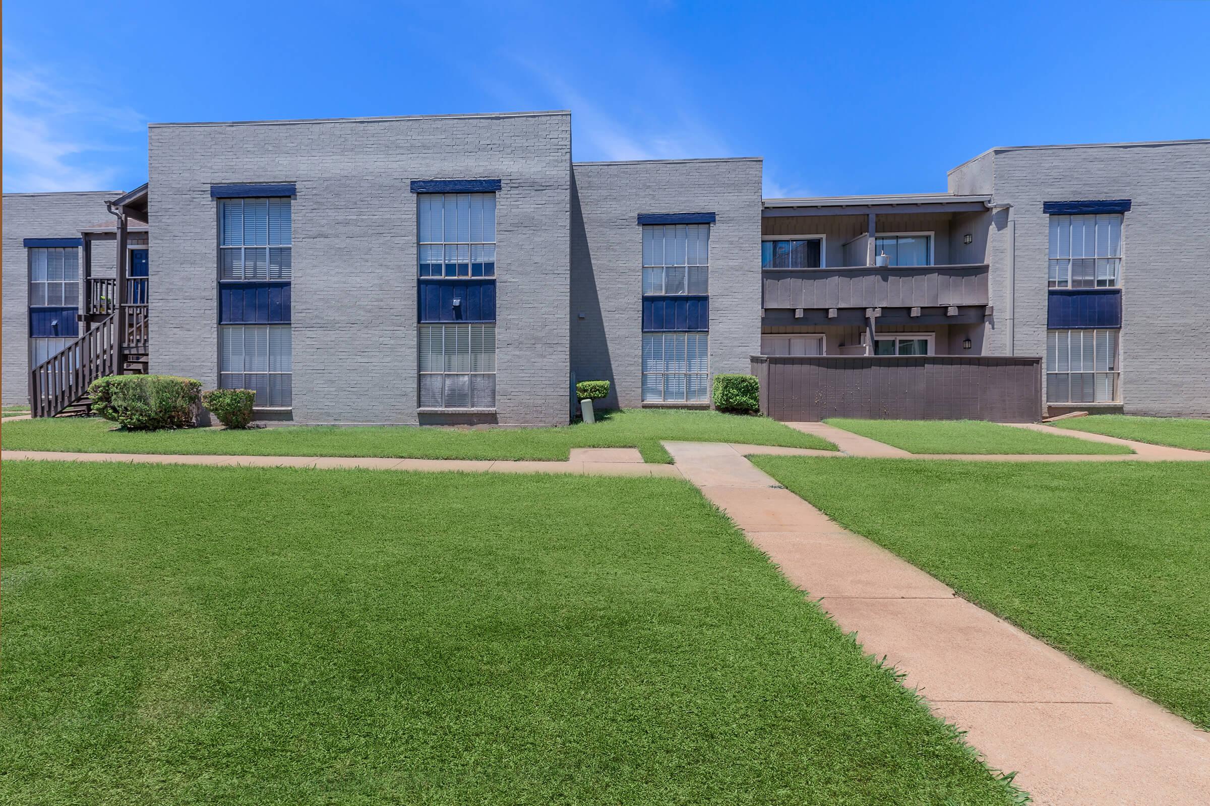 a large brick building with green grass