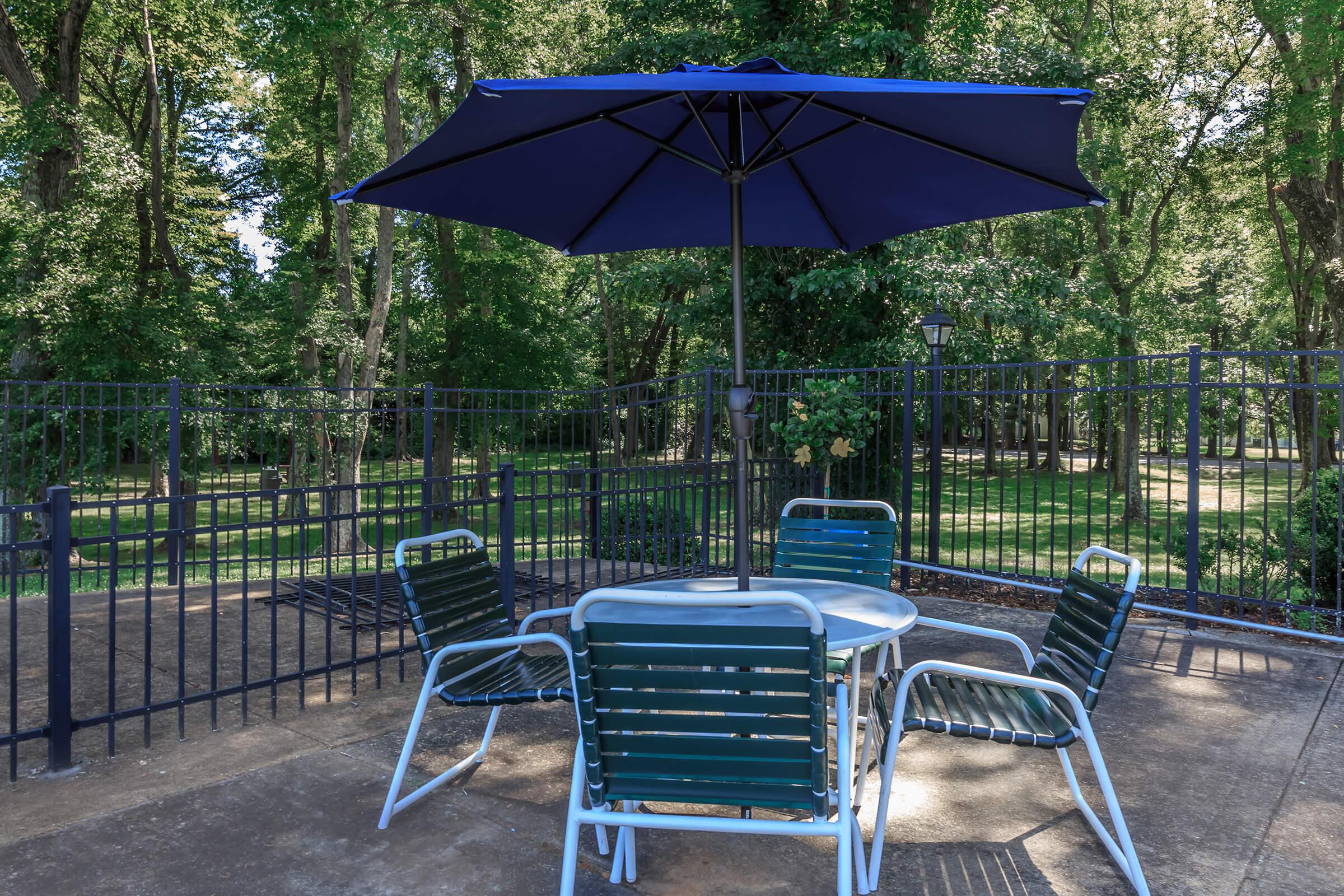 an empty park bench next to a blue umbrella