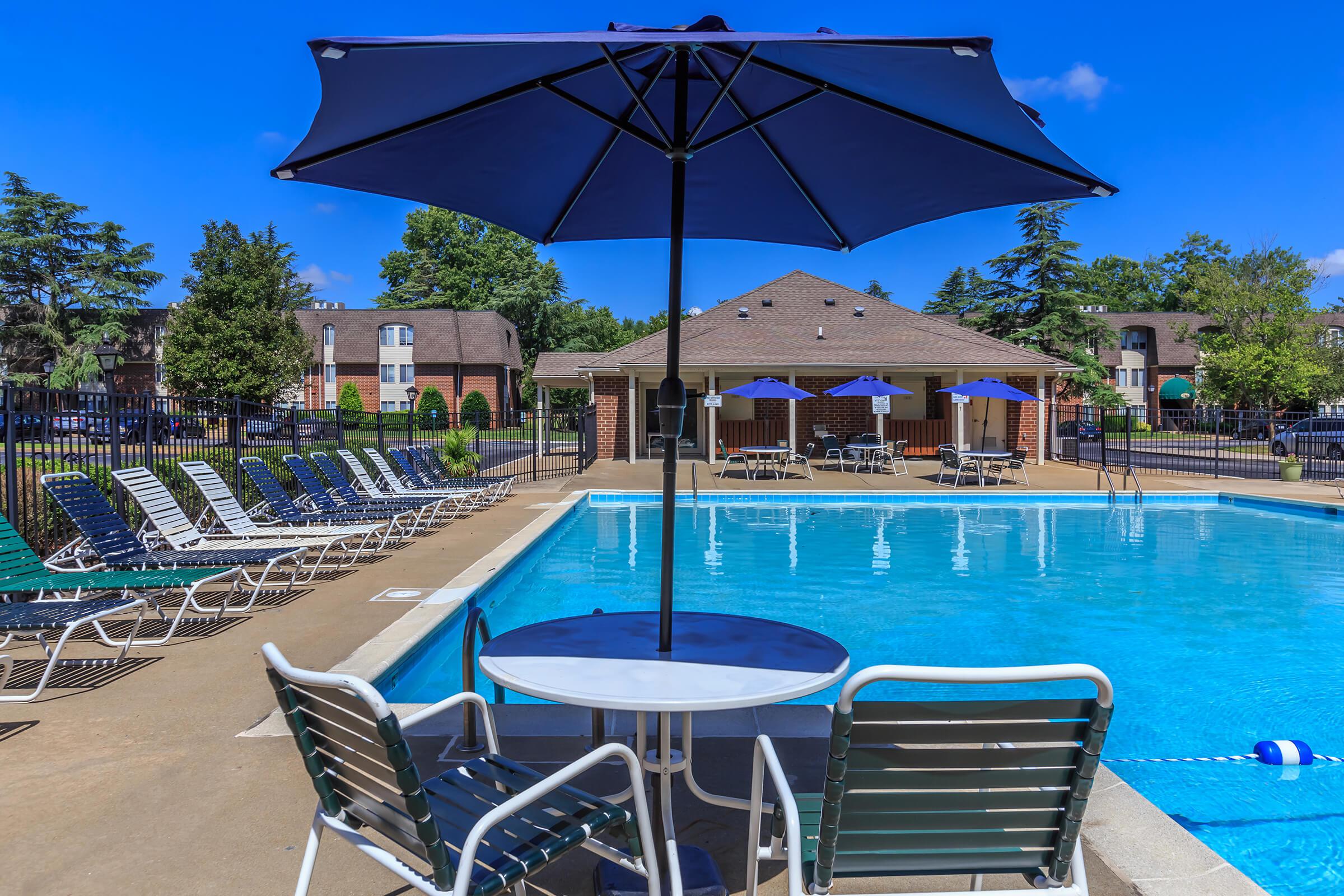 a group of lawn chairs sitting on a pool table with a blue umbrella