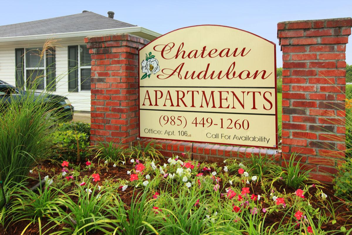 a sign in front of a brick building with a red flower