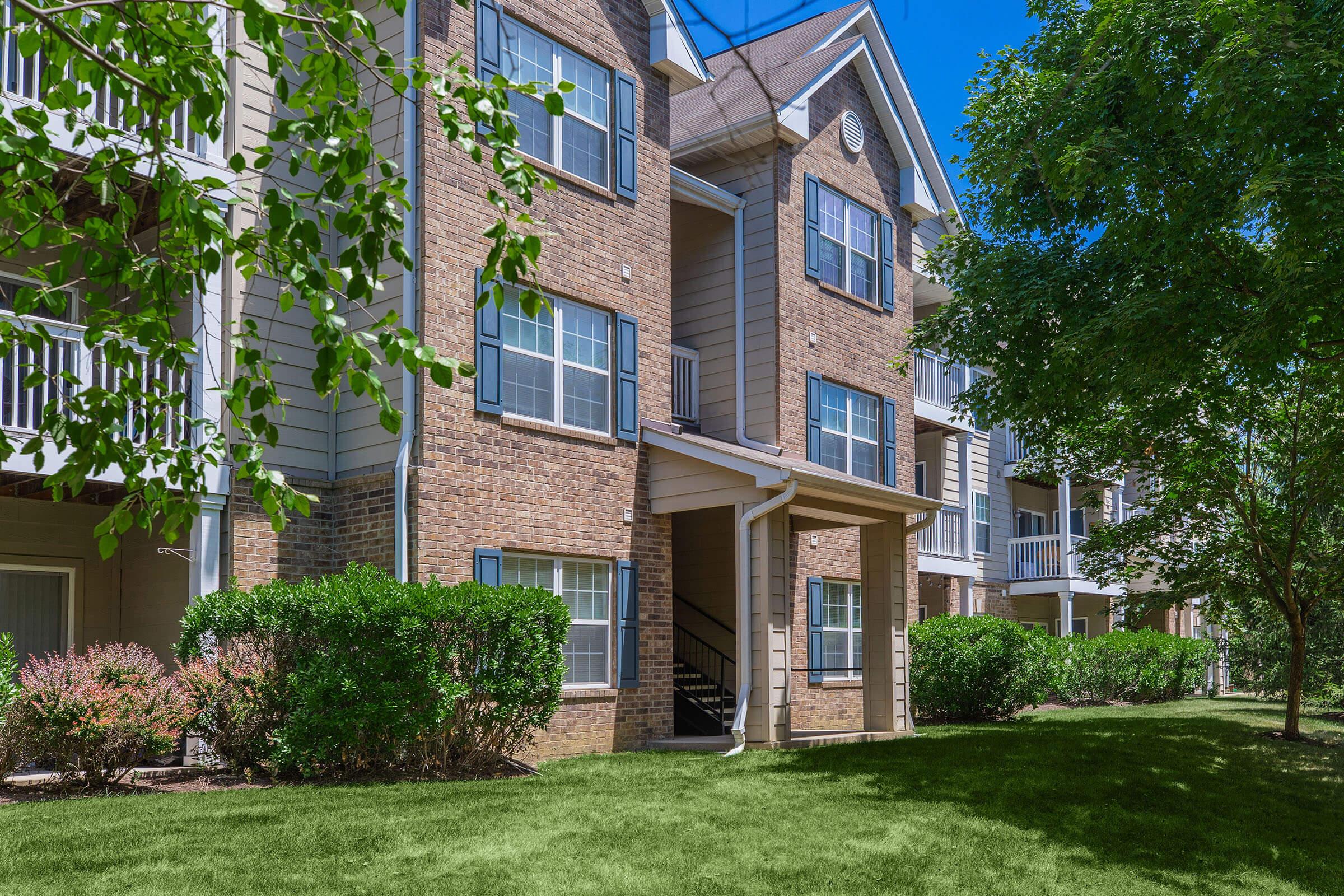 a house with bushes in front of a brick building