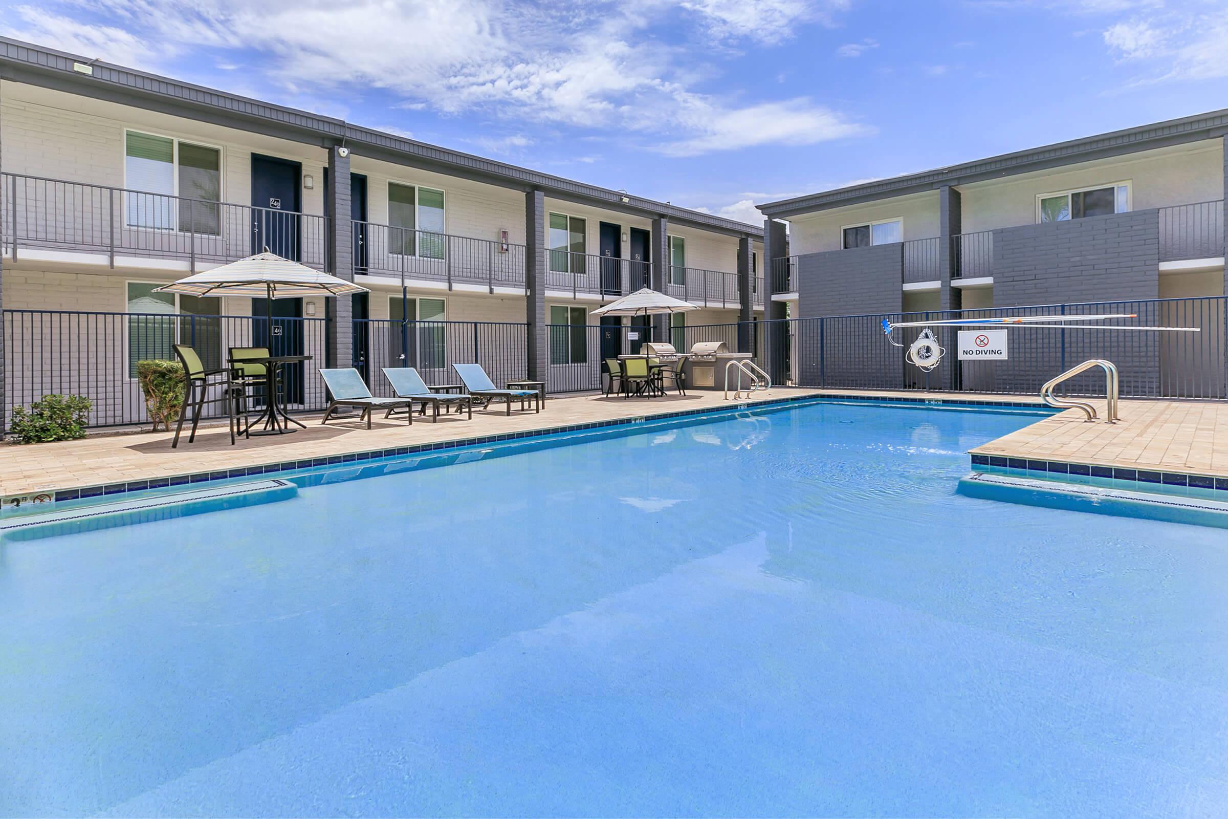 Large outdoor swimming pool surrounded by 2 story apartment buildings