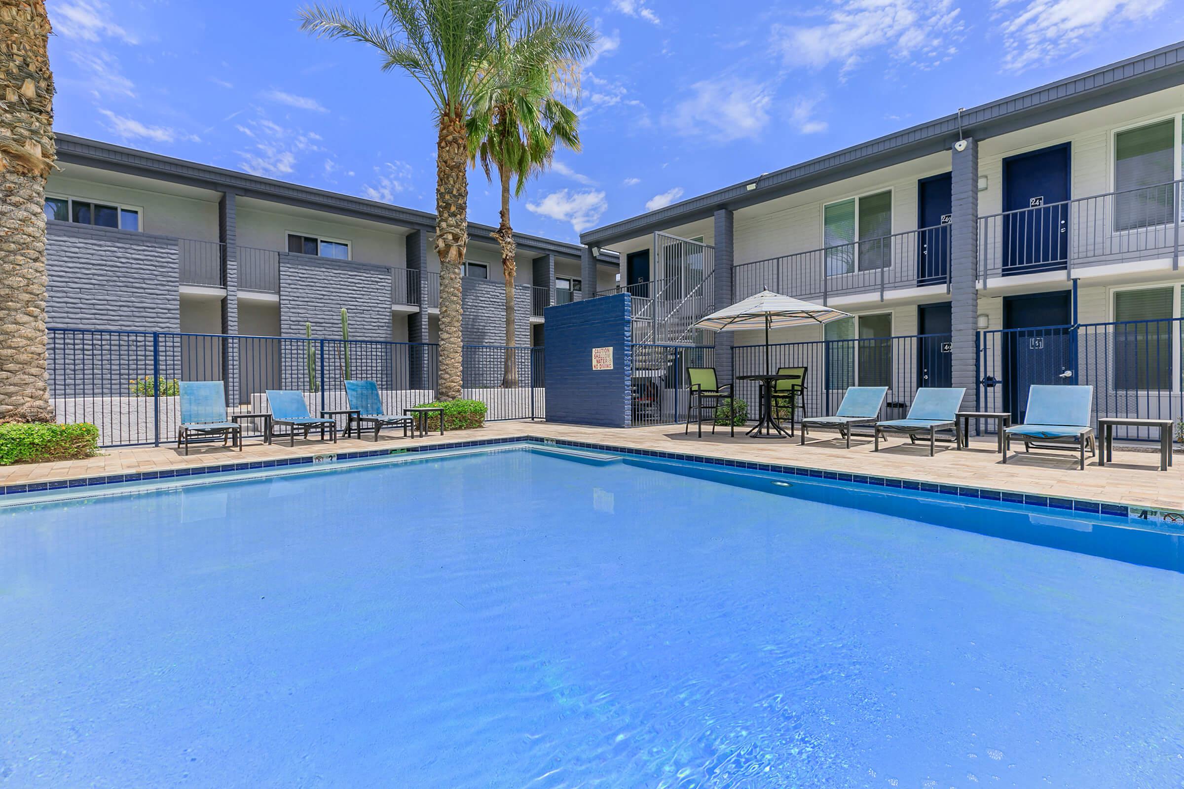 Blue sparkling resort-style pool and pool chairs at Rise Canyon West Phoenix apartments