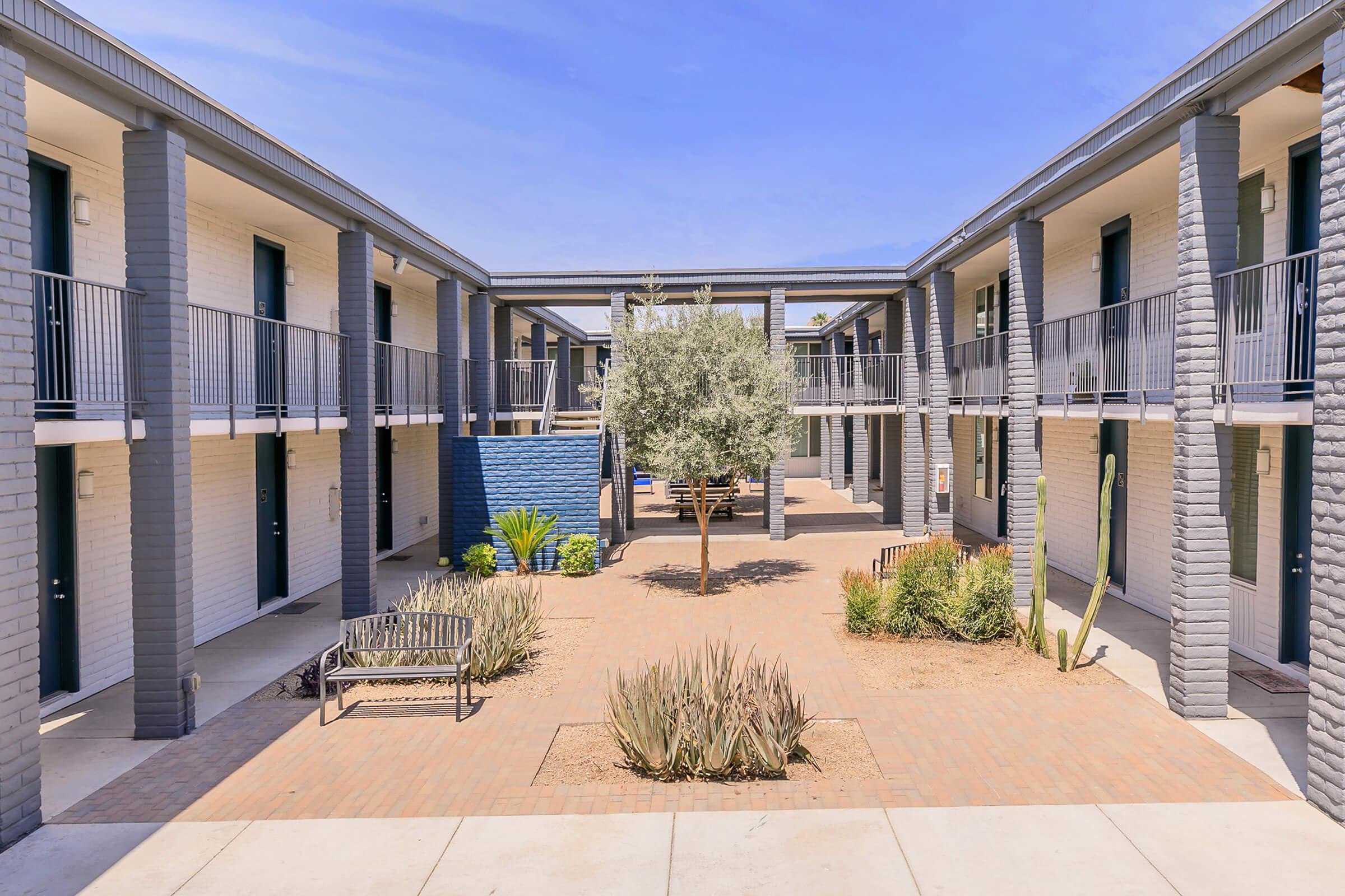 Landscaped courtyard nestled between two large Phoenix apartment buildings connected by an overpass archway