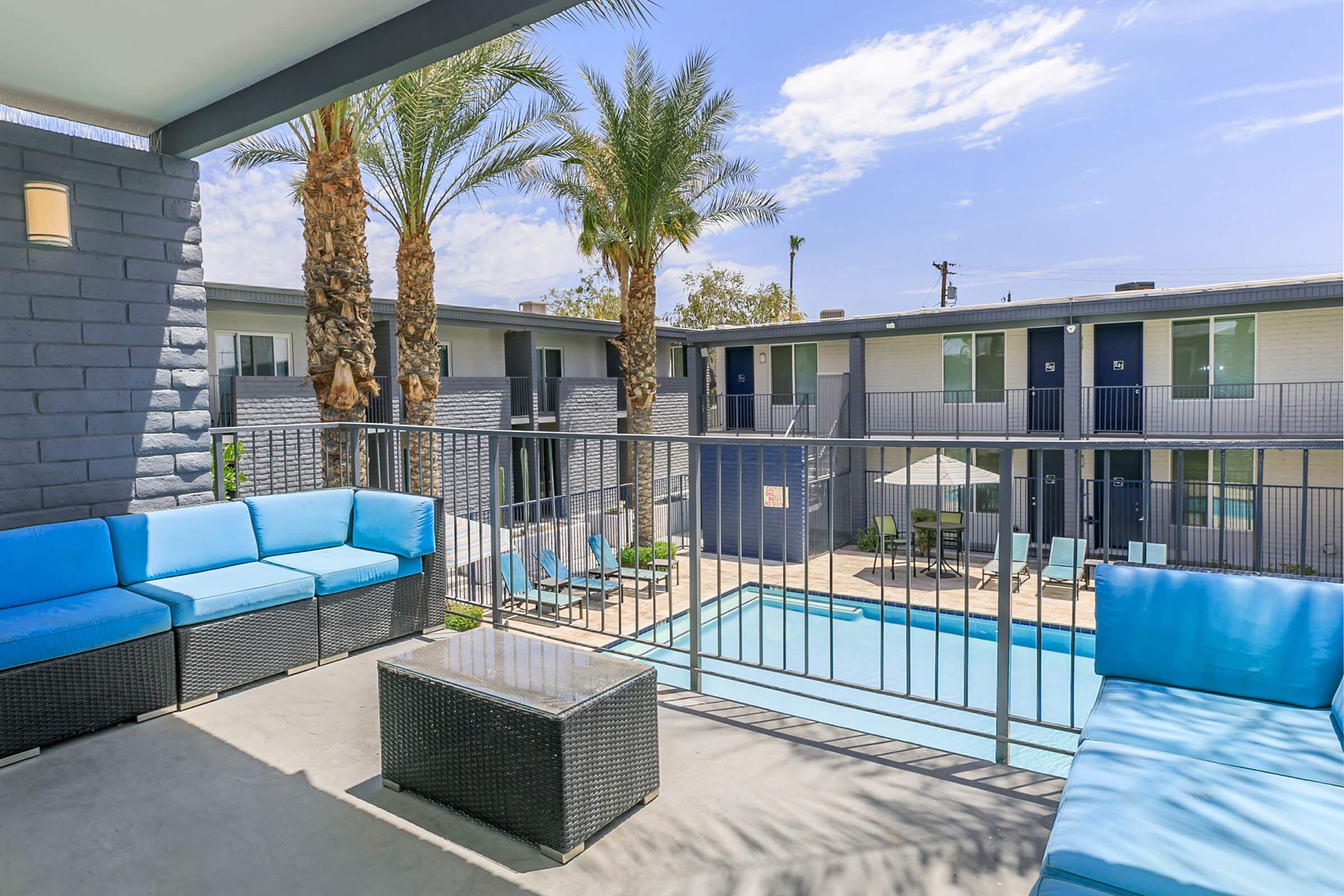 Outdoor balcony with large patio set overlooking a resort-style pool at Rise Canyon West Phoenix apartments