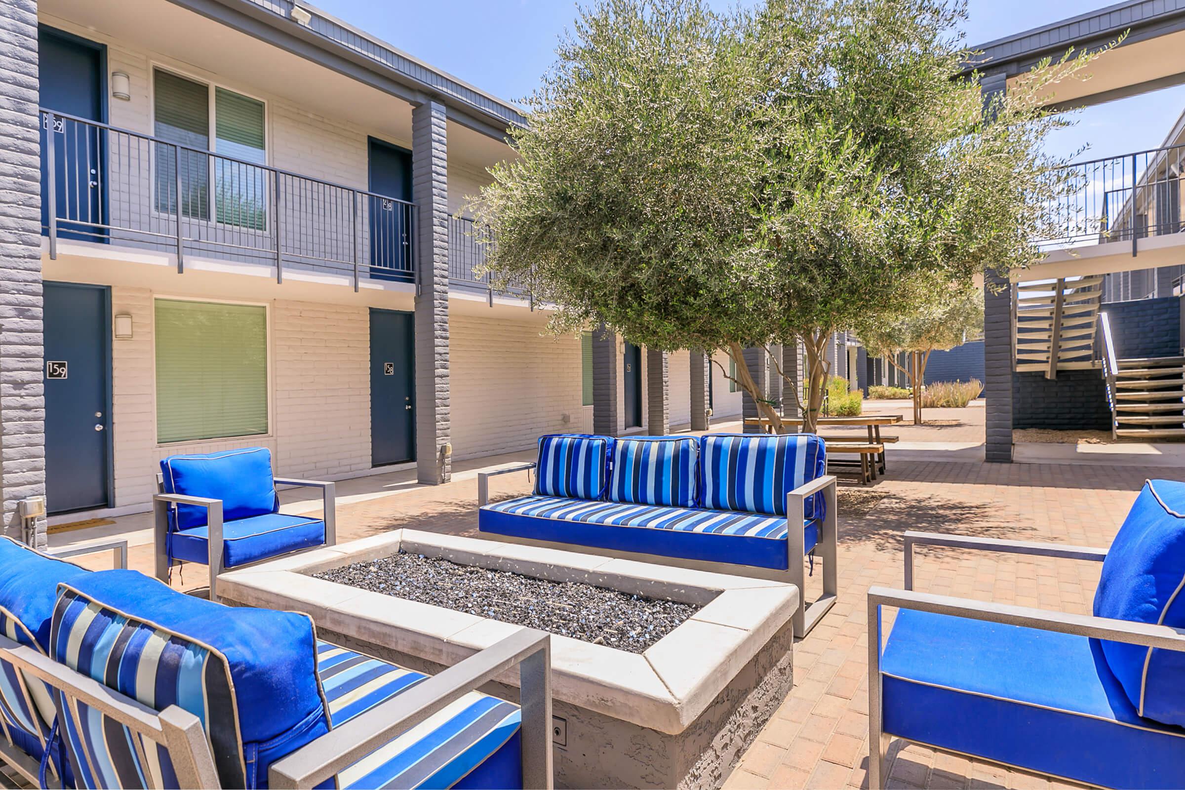 Outdoor fire pit area with blue lounge chairs at Rise Canyon West apartments in Phoenix