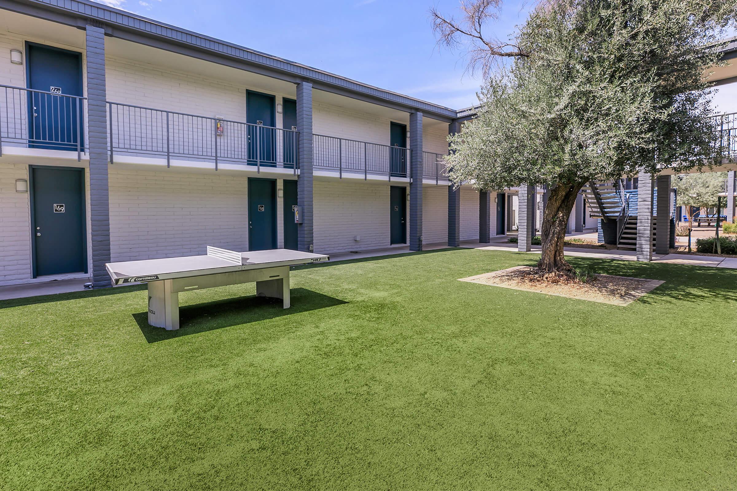 Outdoor grass courtyard nestled next to a large two-story Phoenix apartments
