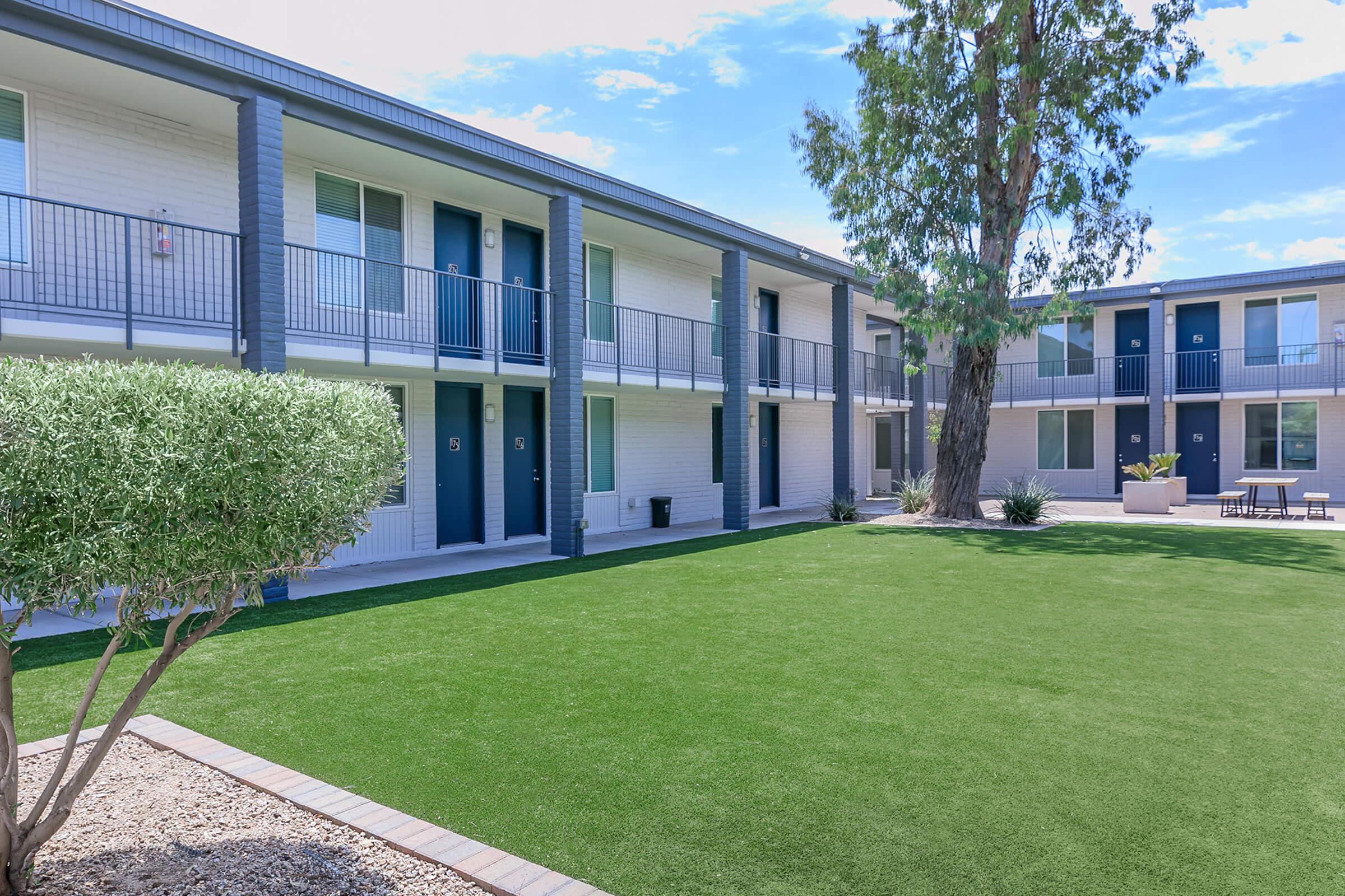 Outdoor grassy courtyard area in front of a two-story Rise Canyon West apartment building