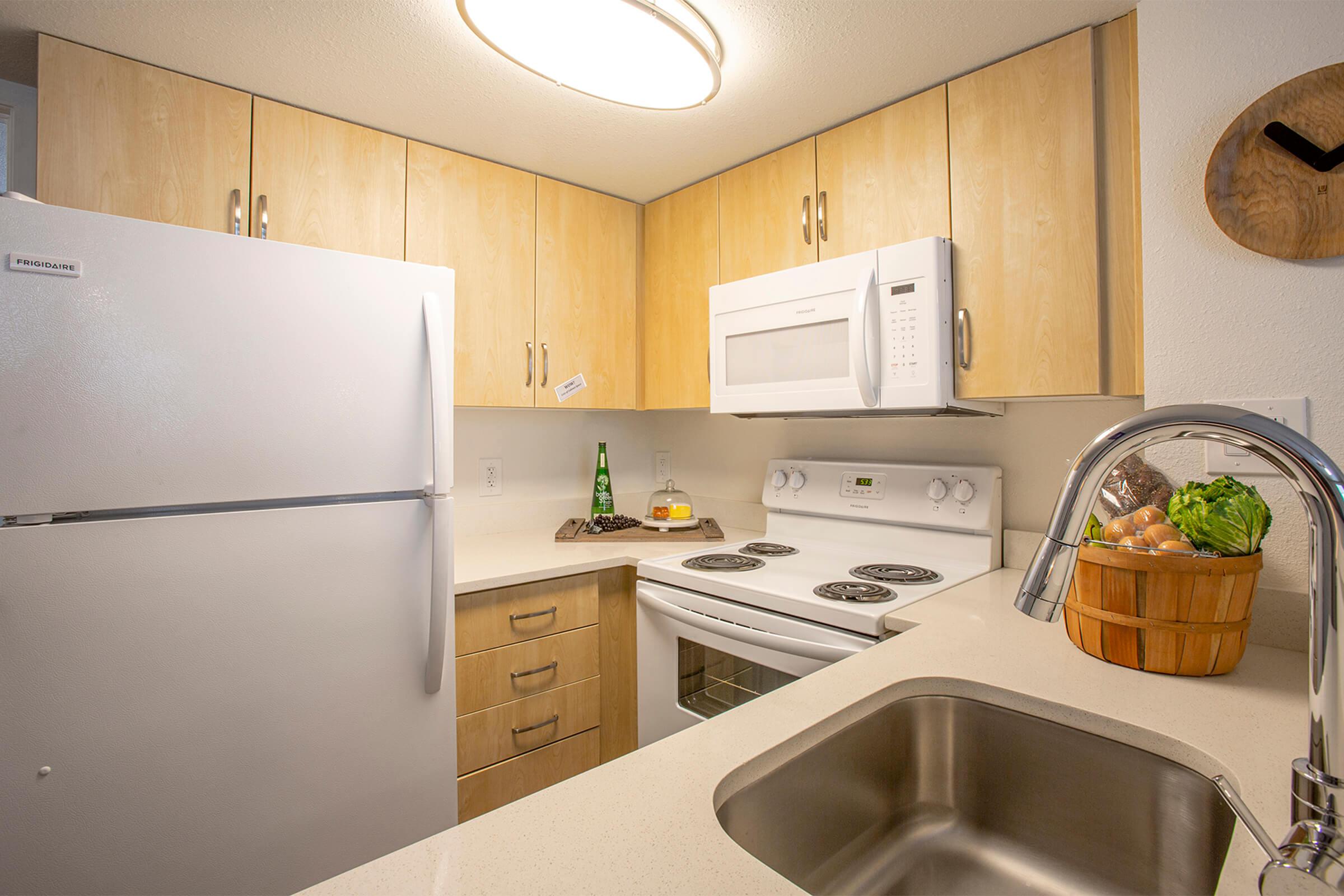 Phoenix, AZ kitchen with large quartz countertops, light wood cabinets, and white appliances