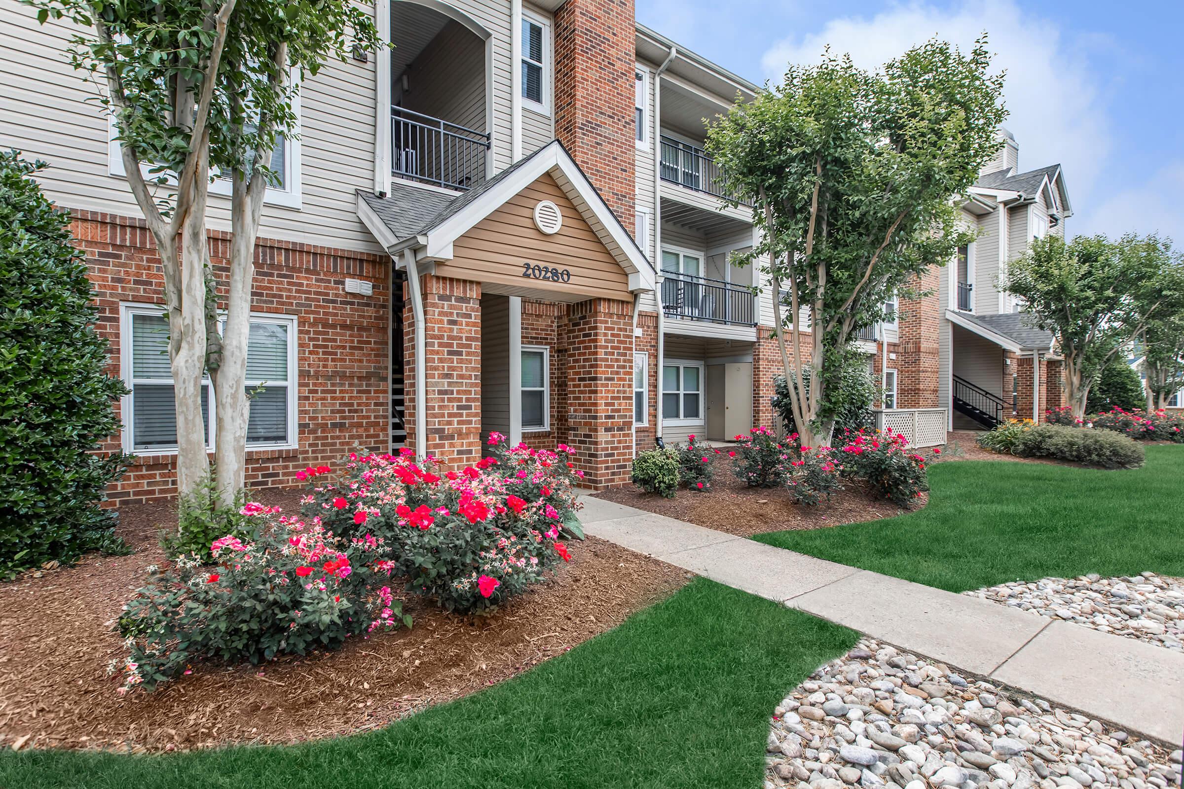 a close up of a flower garden in front of a brick building