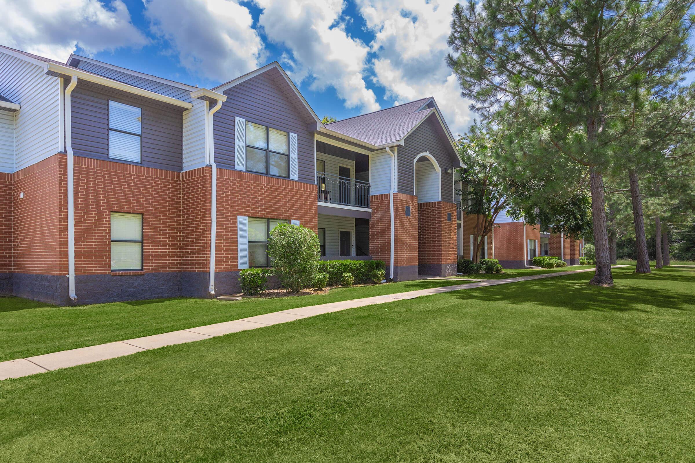 a large brick building with grass in front of a house