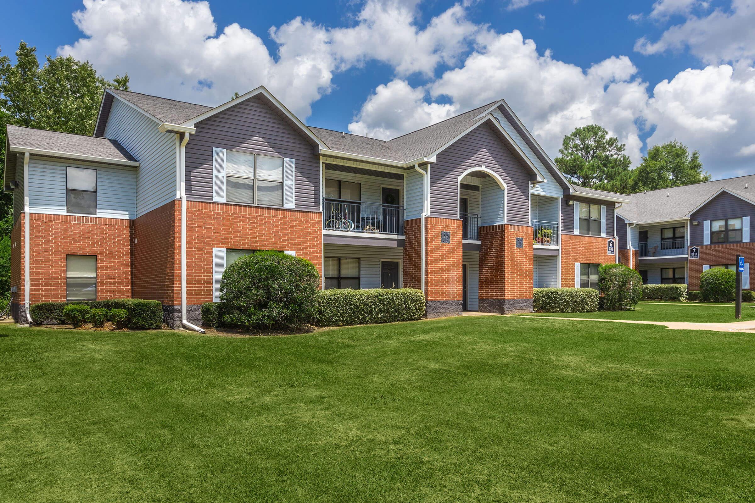 a large brick building with grass in front of a house