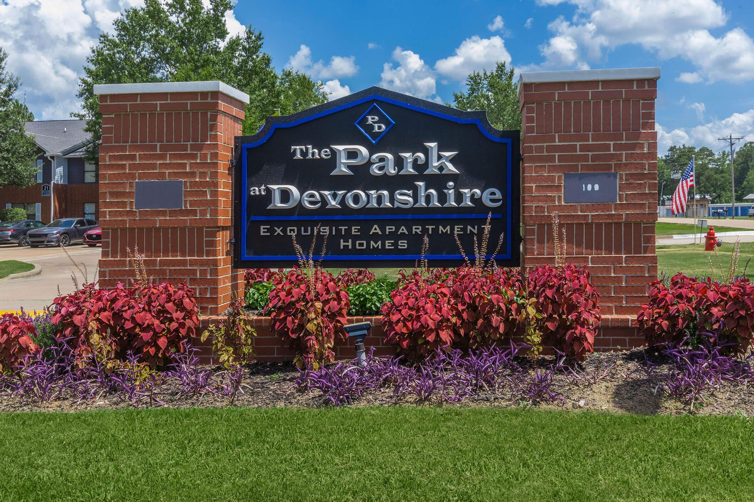 a colorful flower garden in front of a brick building