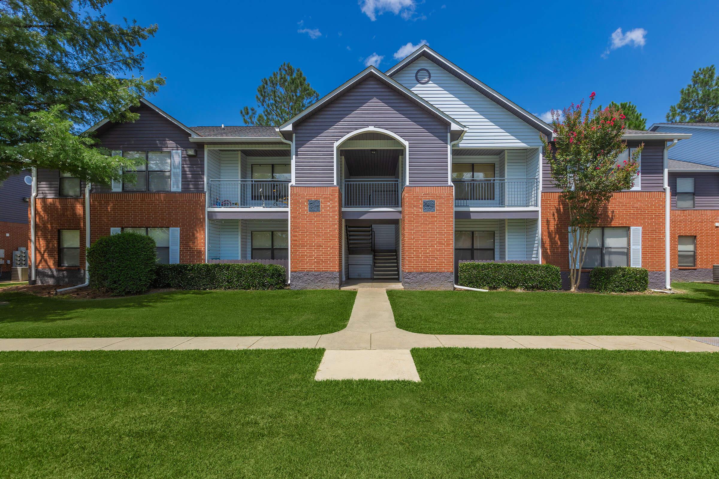 a house with a lawn in front of a brick building