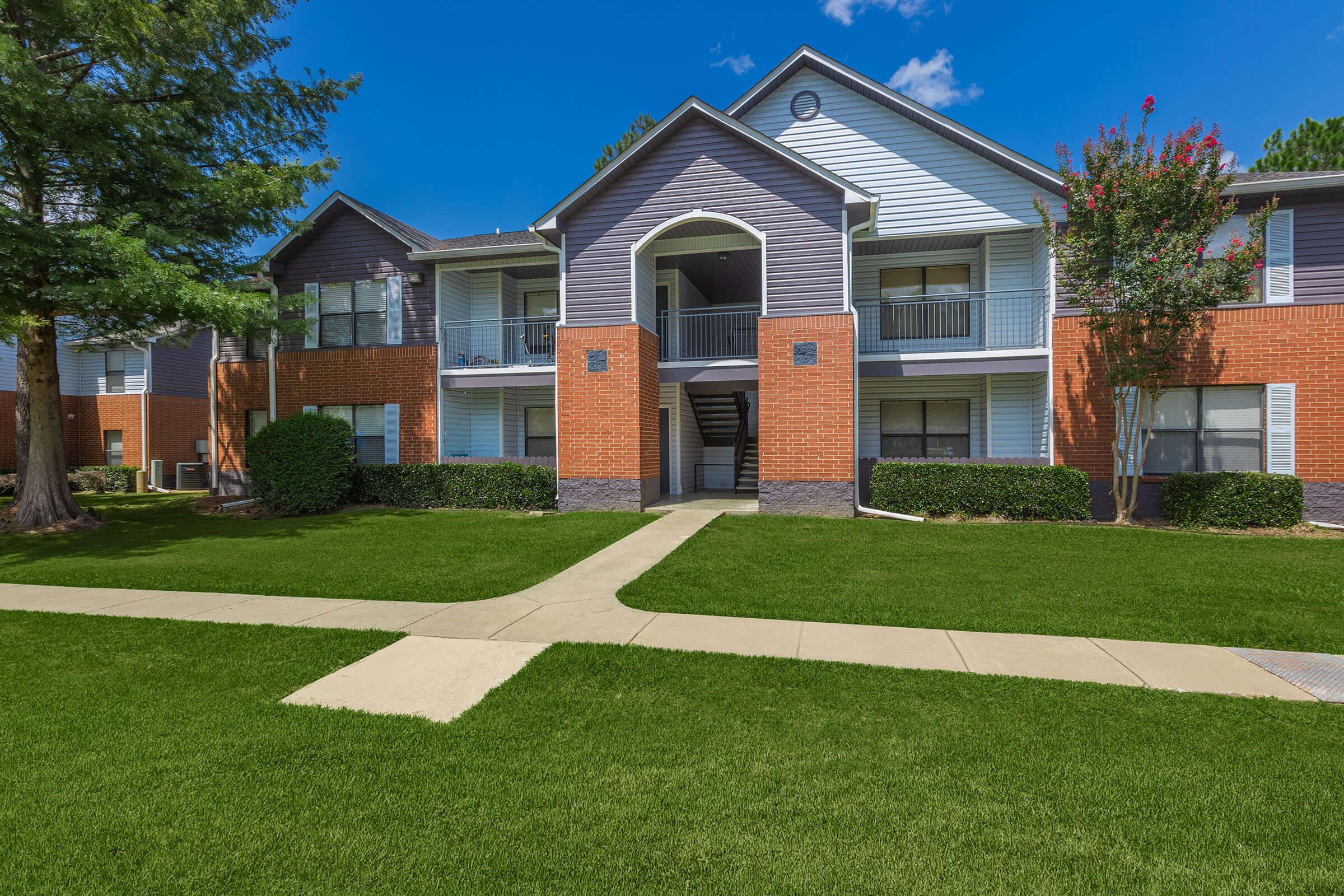 a house with a lawn in front of a brick building