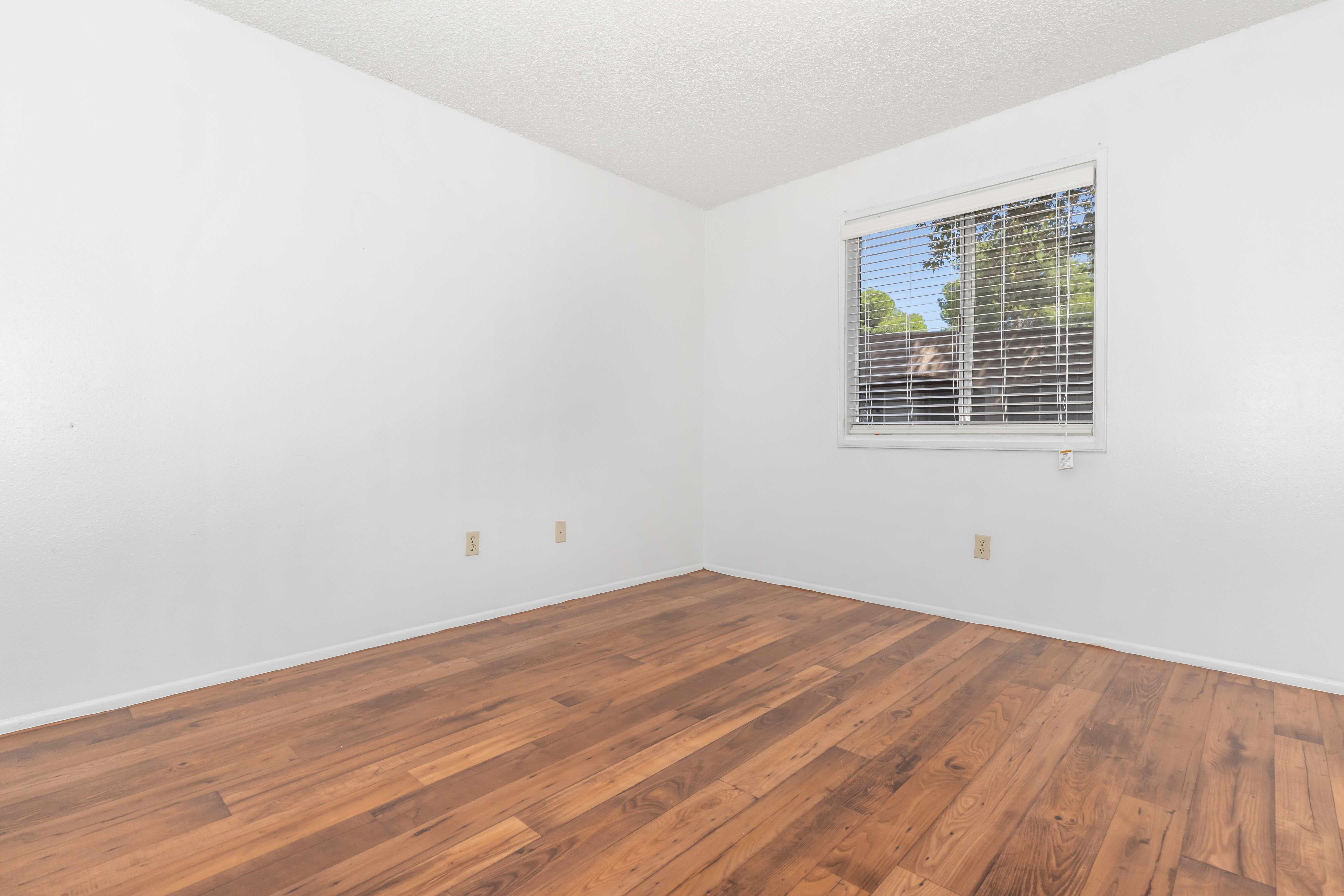 Unfurnished apartment bedroom with wood-look flooring.