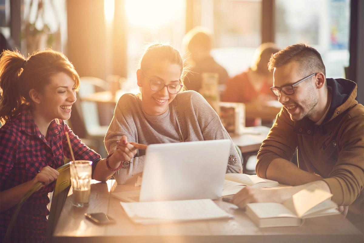 a group of people sitting at a table looking at a laptop